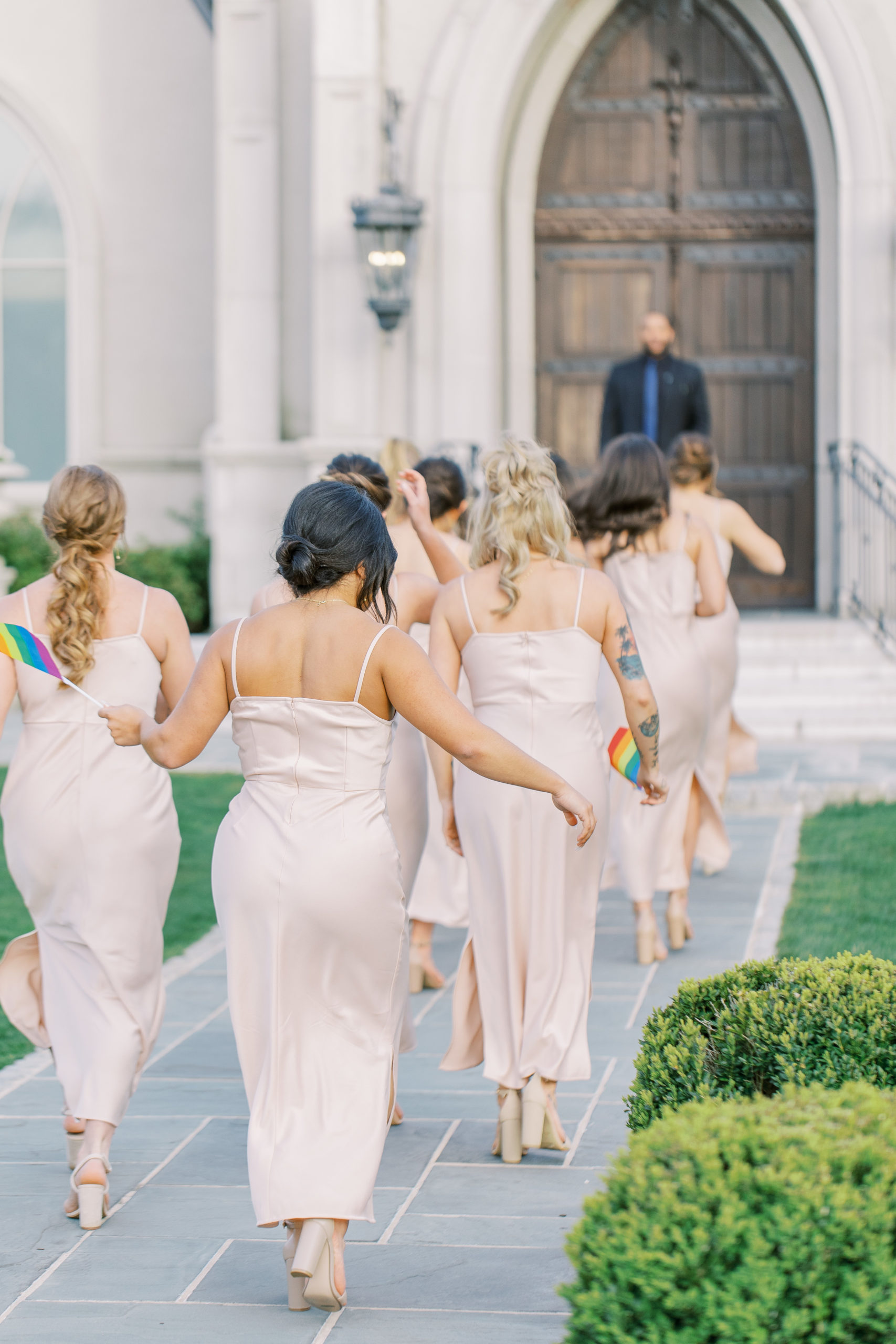 Bridal party walk to line up holding pride flags 