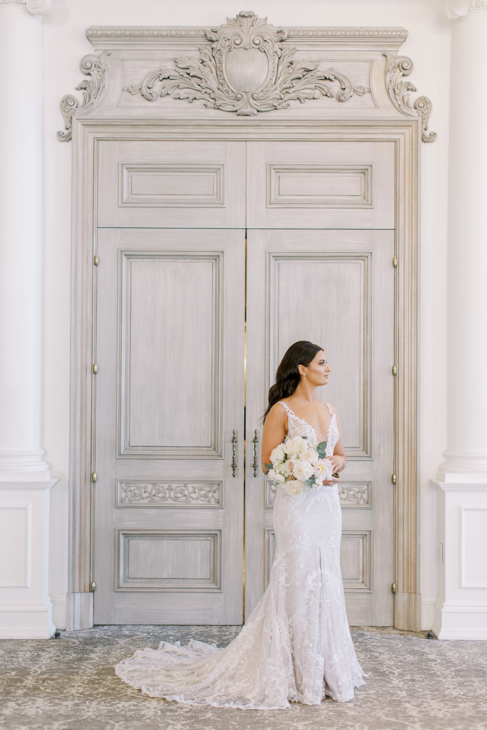 Bride posing holding rose wedding bouquet in front of grand door entrance for a Romantic Park Chateau Wedding Photography