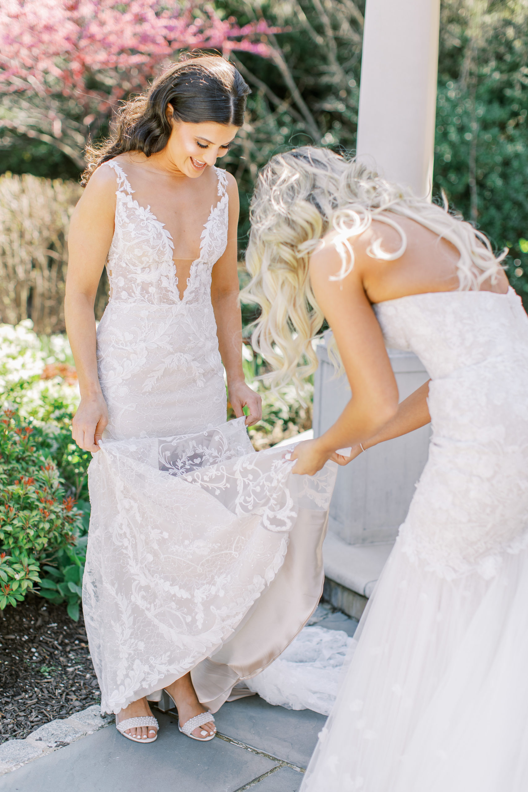 Brides smile and admire dresses in garden 