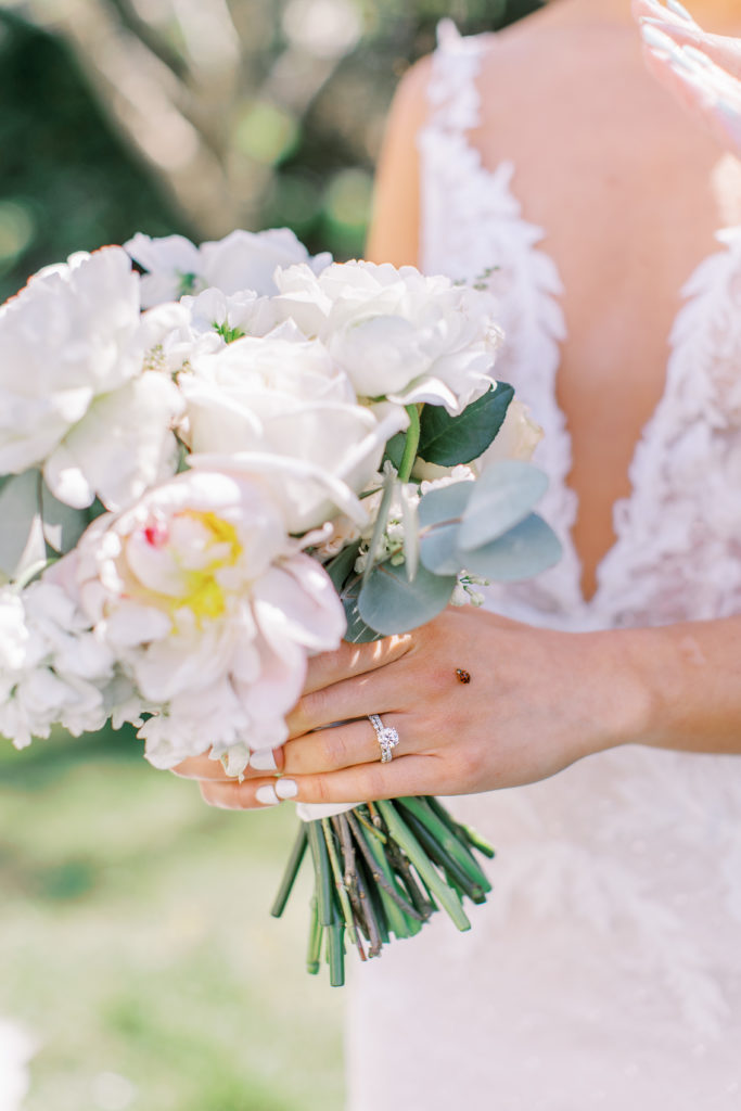 Up close view of rose bouquet with lady bug on bride's hand for a Romantic Park Chateau Wedding Photography