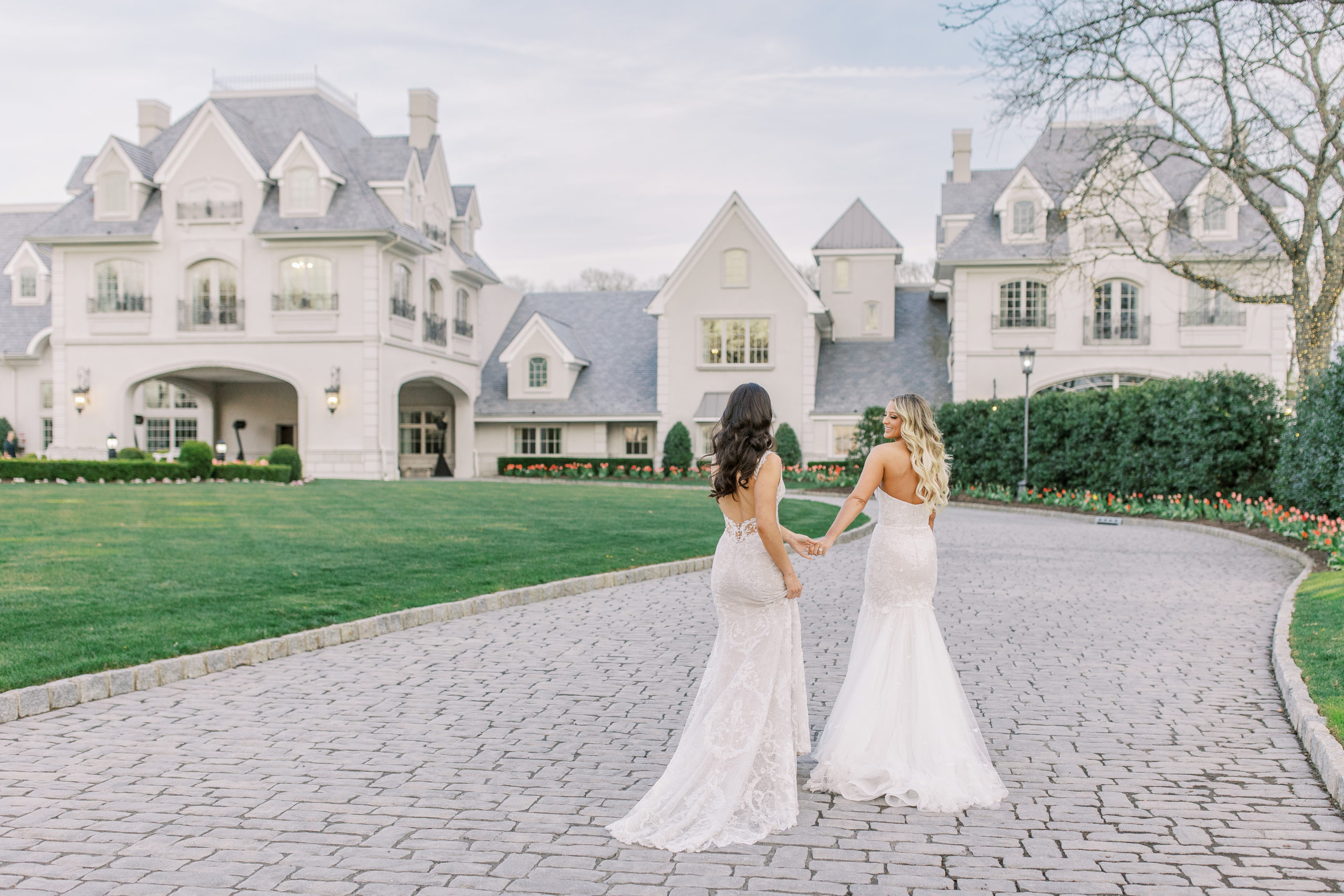 Brides smile and walk along driveway of Chateau venue 