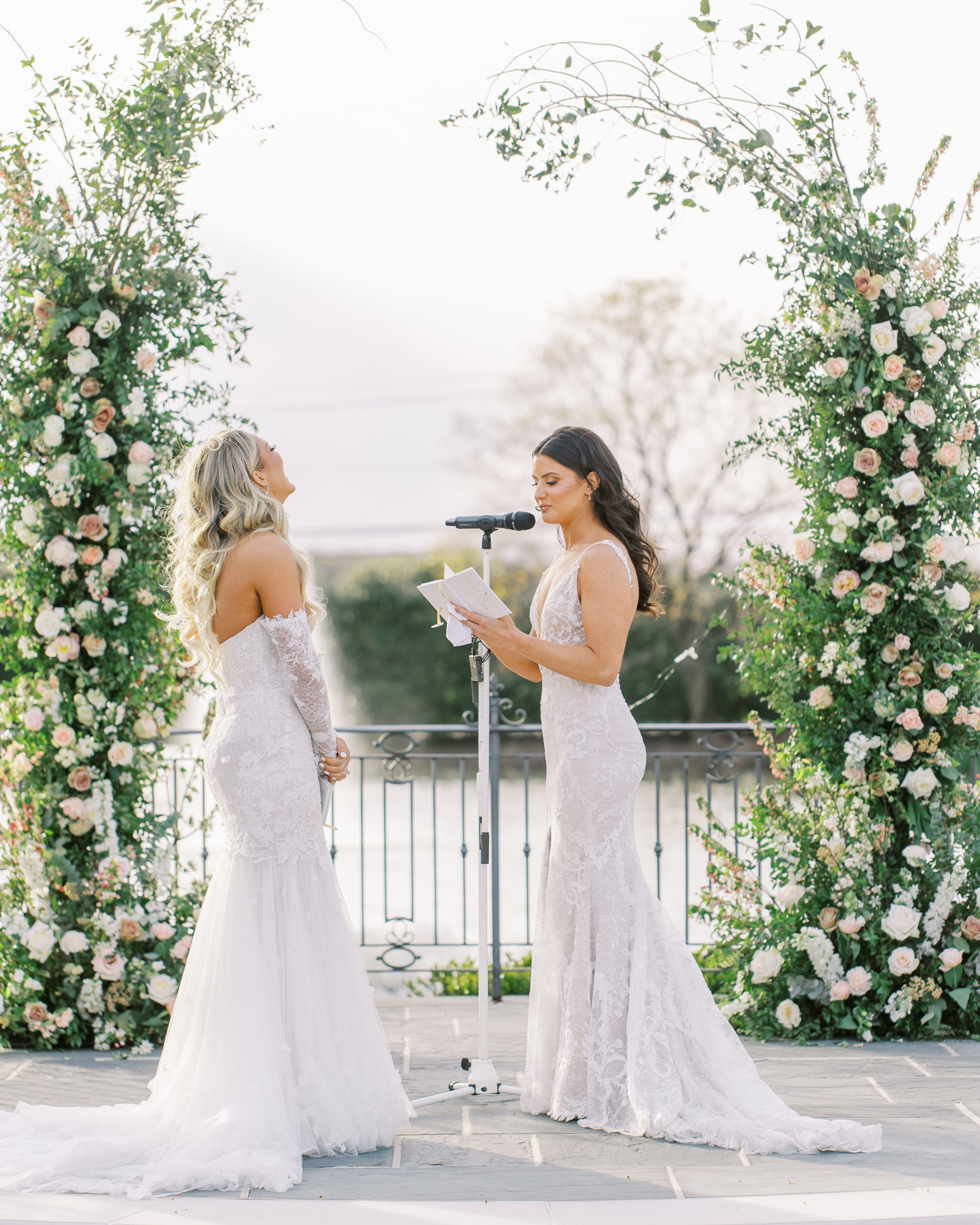 Brides read each other vows under rose arch 