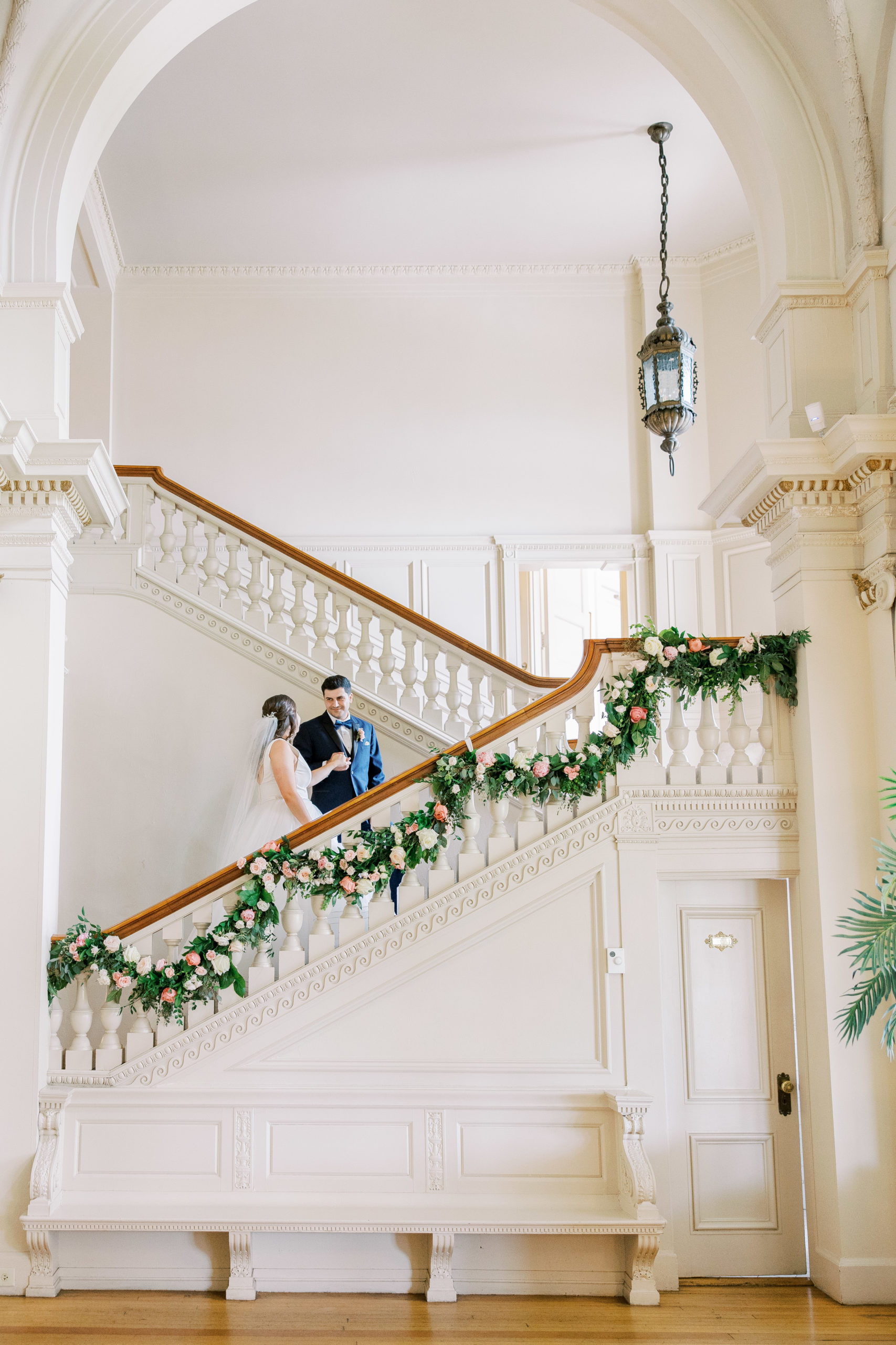 Bride and groom hold hands and smile walking up staircase at Cairnwood Estate Wedding Photography