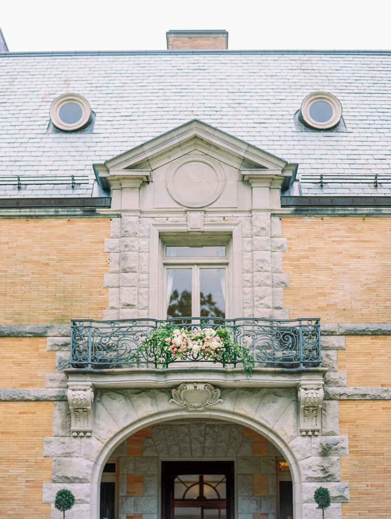 Balcony with roses of french inspired chateau built of limestone and brick 