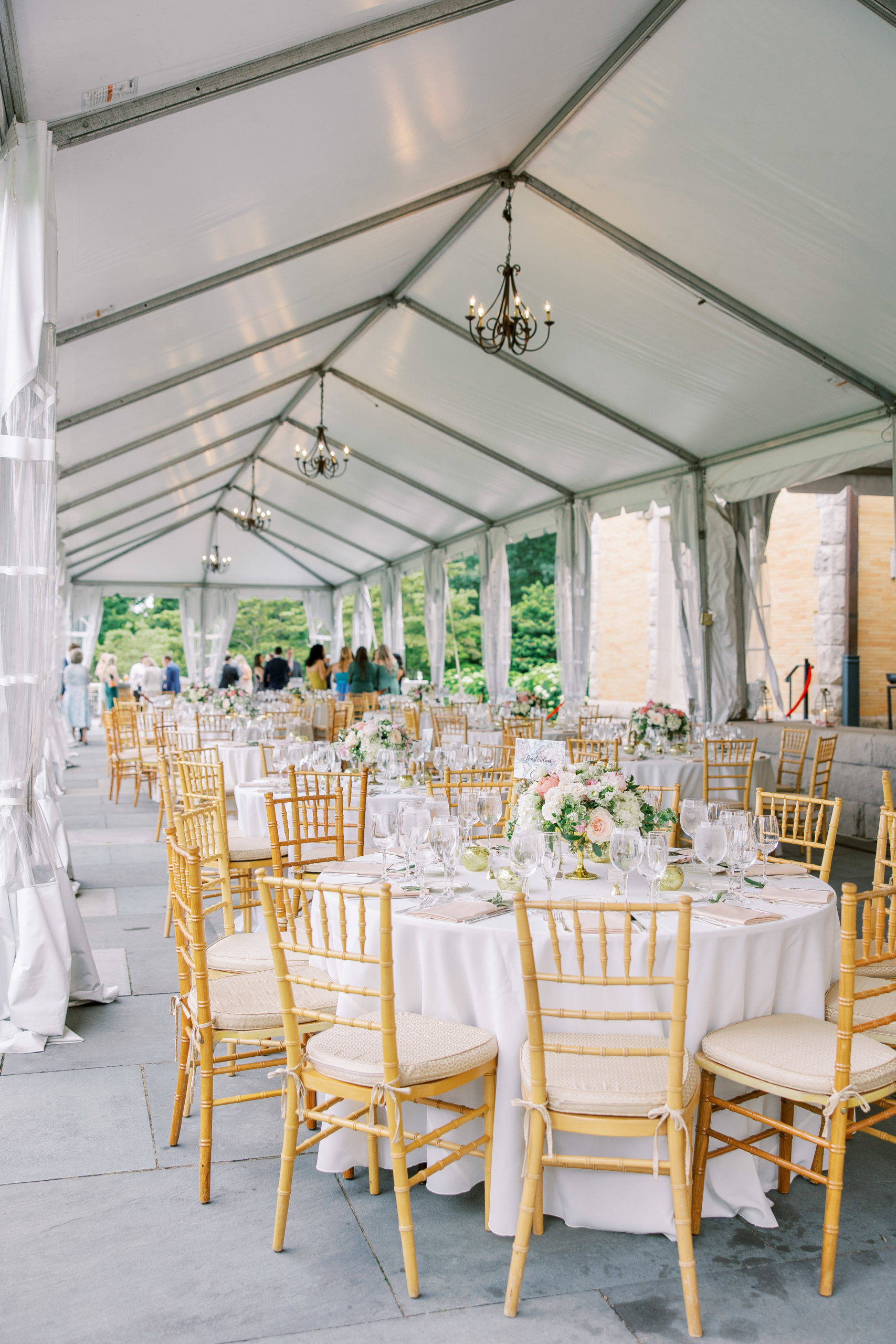Wededing reception tent with tables and rose centerpieces and small black fixture chandeliers for Cairnwood Estate Wedding Photography