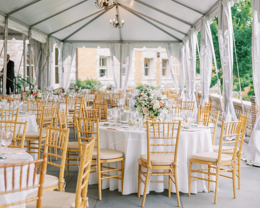 Wedding reception table seating with rose center pieces and gold painted chairs under tent for Cairnwood Estate Wedding Photography