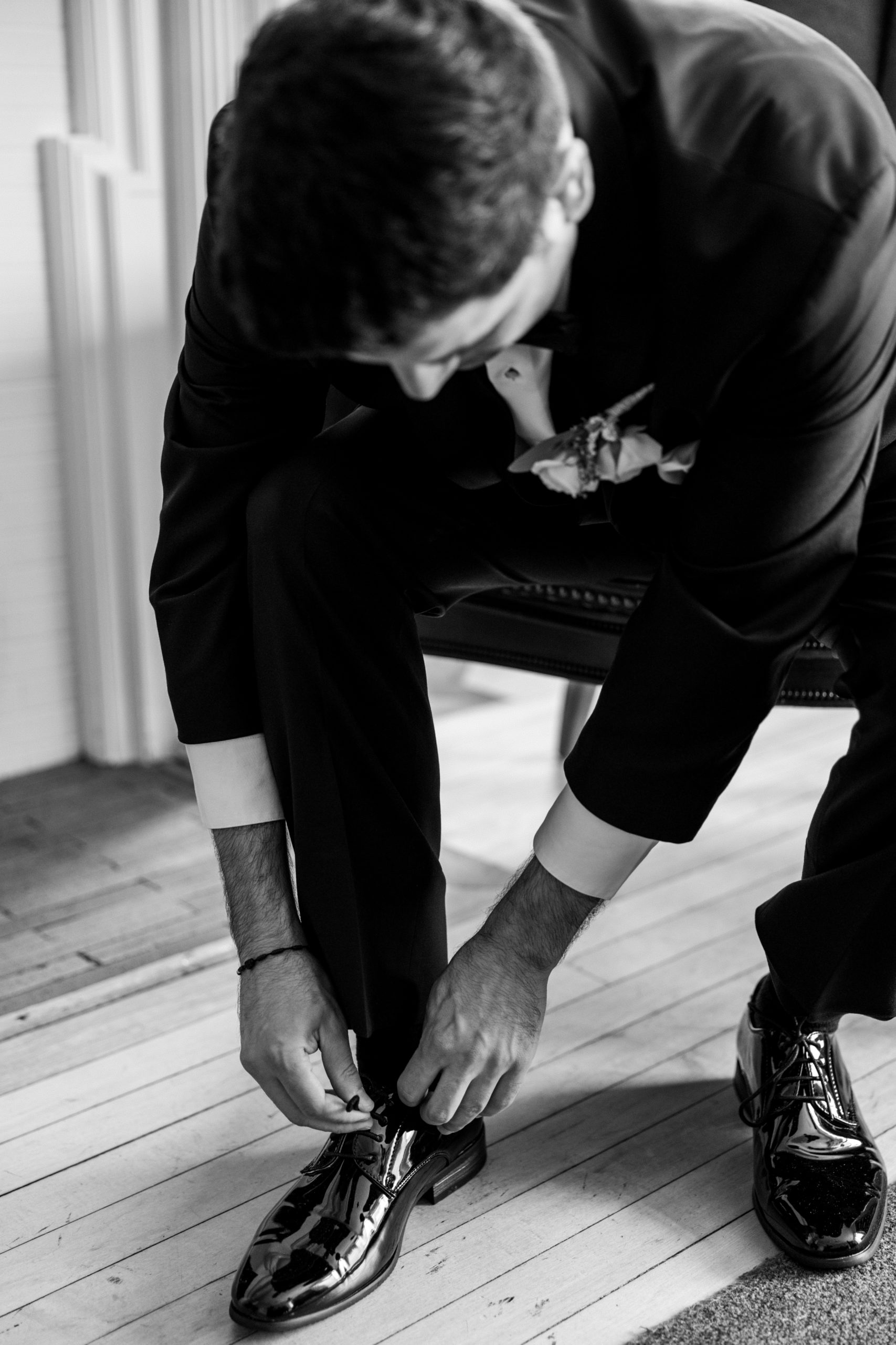 Groom sits in chair and ties his shoes 
