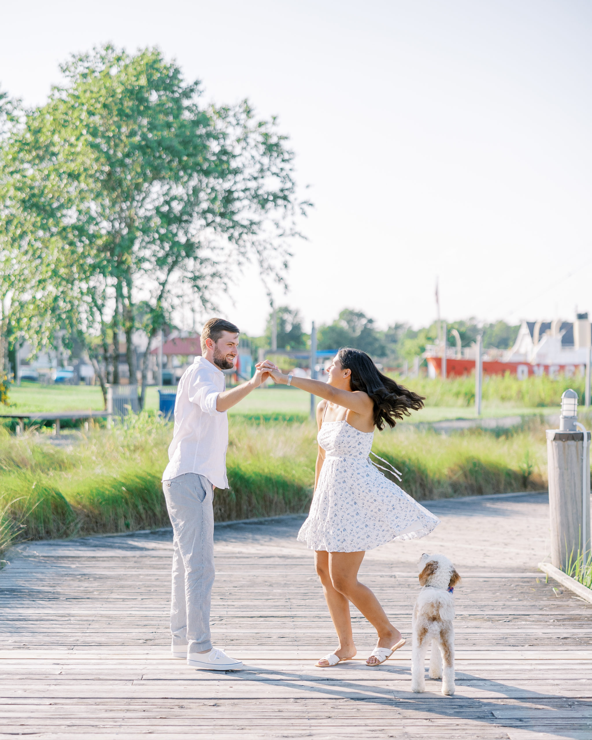 Couple dances on boat dock with dog looking up at them for Summer Lewes Engagement Session
