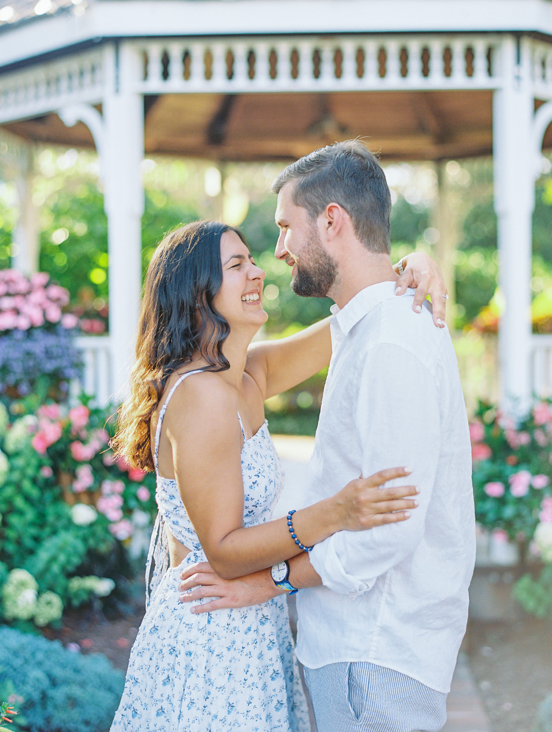 Couple laughs and embraces in front of gazebo garden 