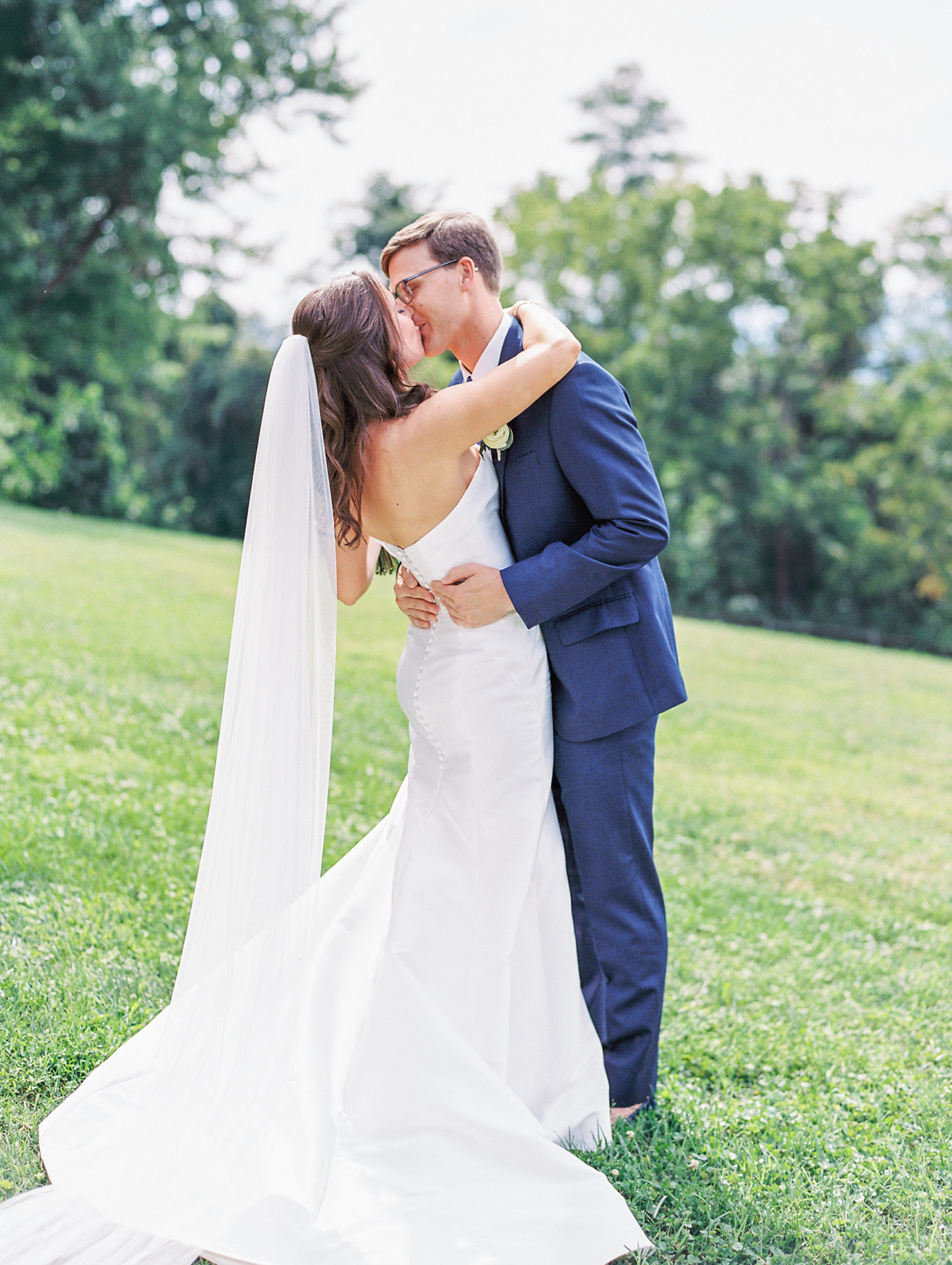 Bride and groom share a kiss outside on mountaintop landscape 