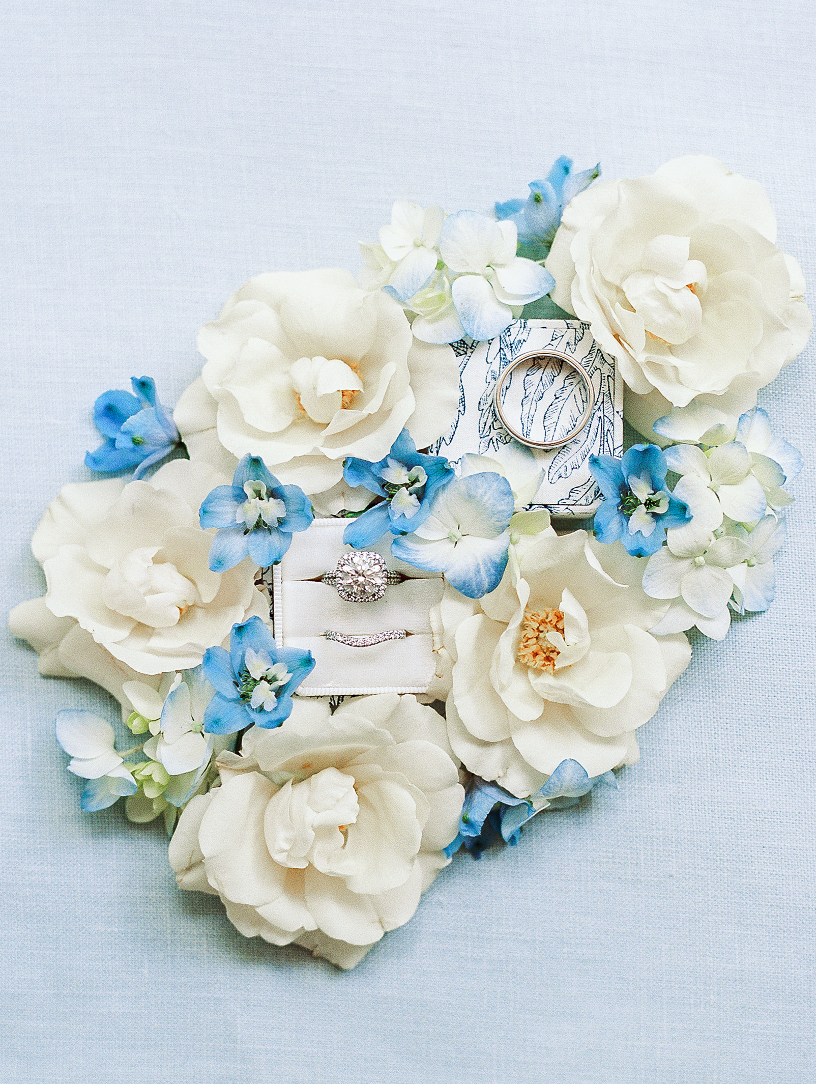 Wedding rings and white and blue flowers displayed neatly