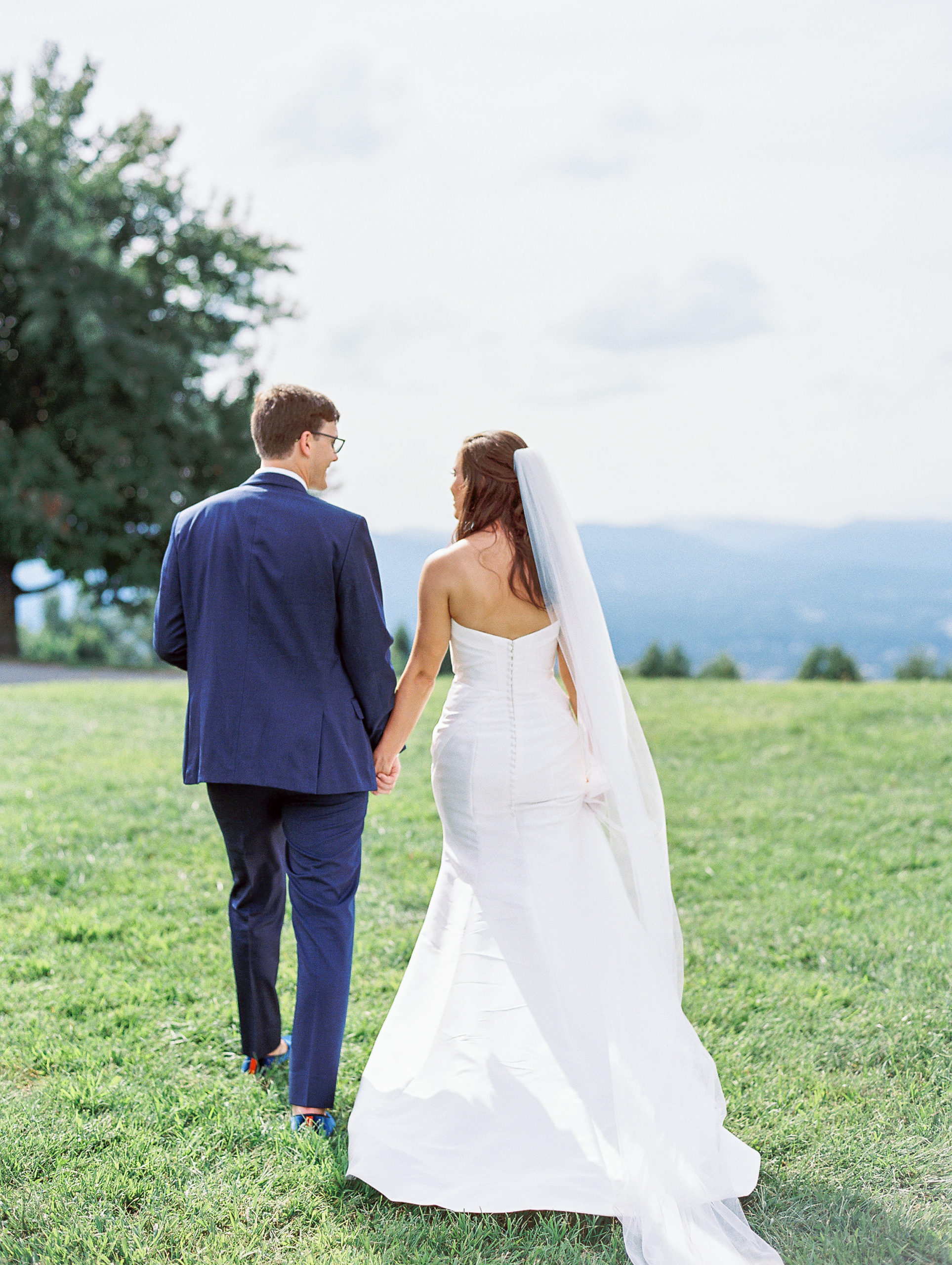 Bride and groom hold hands and walk away on mountaintop landscape for Charlottesville Wedding Photography
