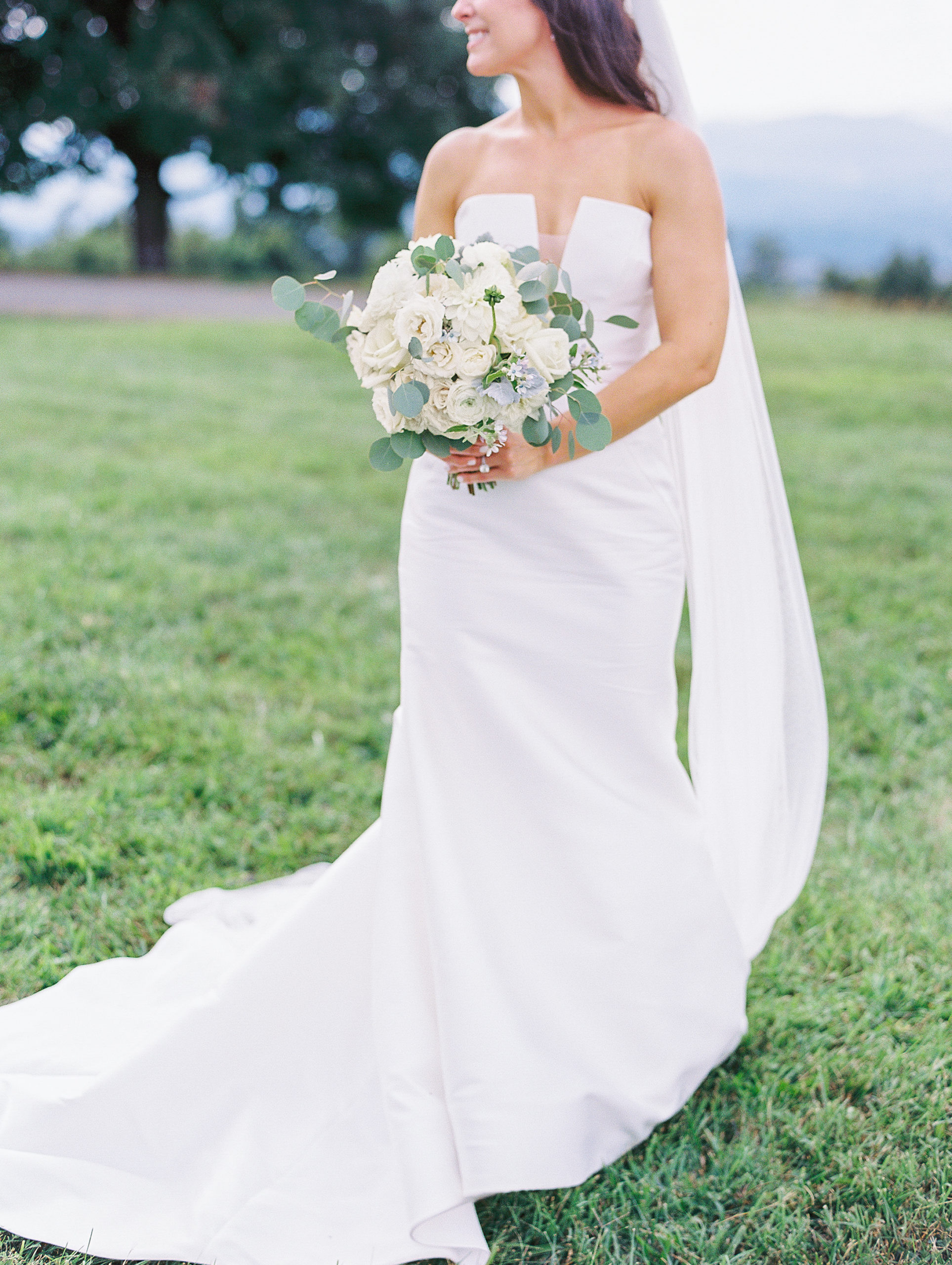 Bride looks to the side and holds white rose bouquet 