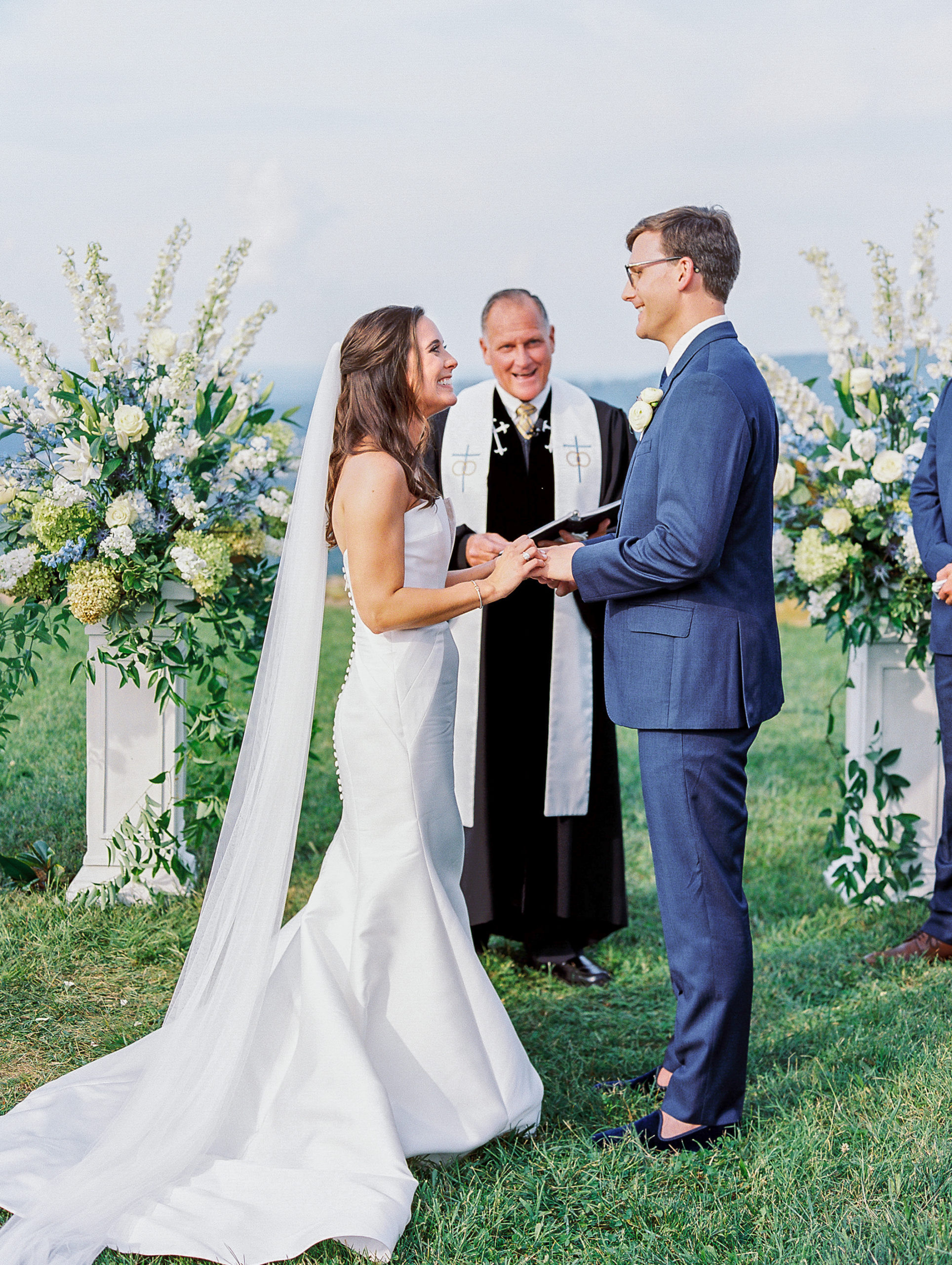 Bride and groom hold hands at the altar with large bouquets atop mountaintop 