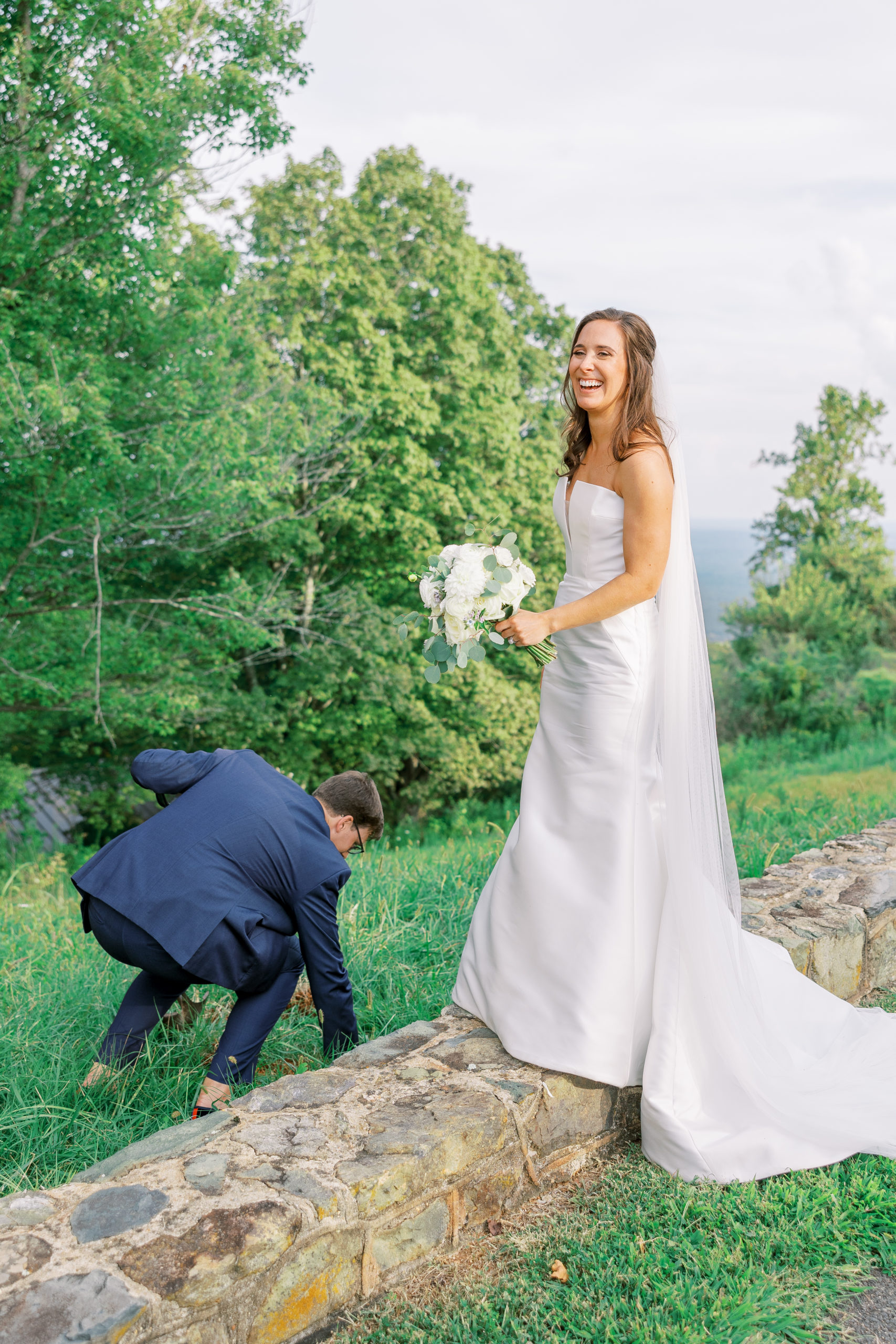 Bride laughs at groom as he is bending down to retrieve something for Charlottesville Wedding Photography
