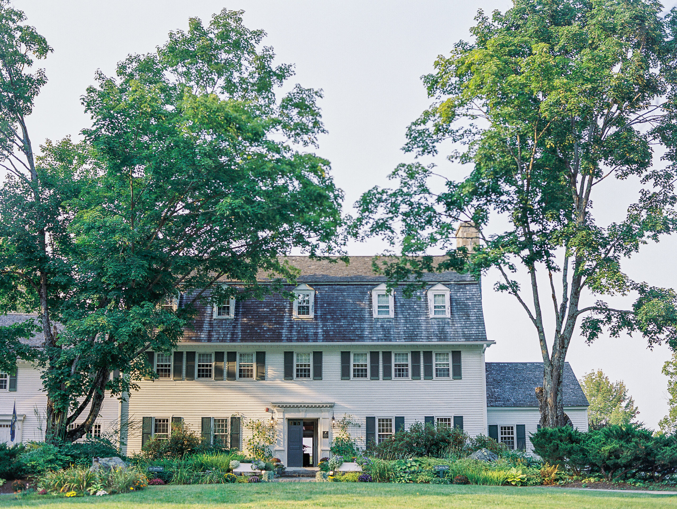 White paneled house with green landscape and trees for New Hampshire Wedding Photography