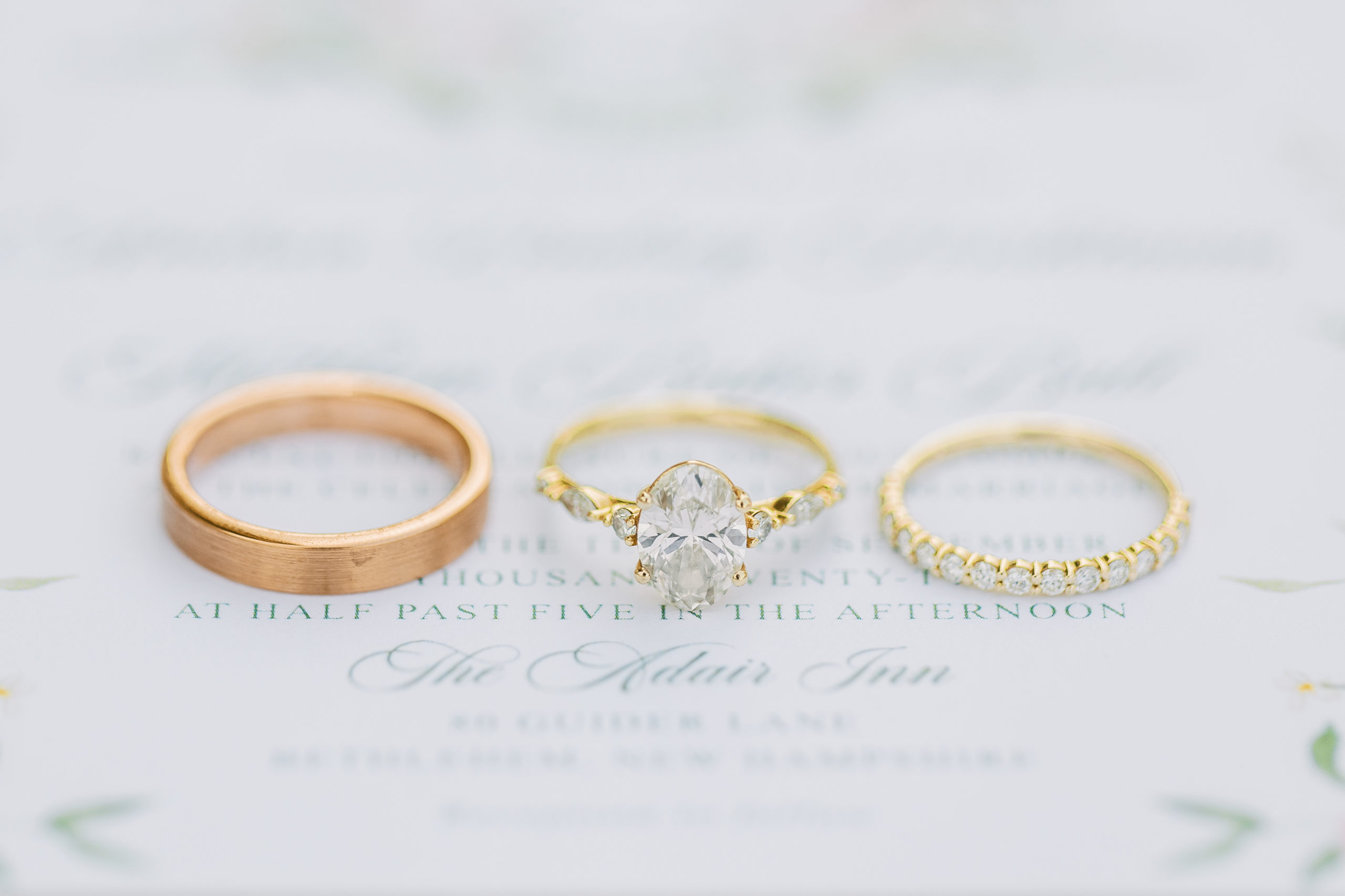 Up close view of wedding rings and band on top of wedding invitations