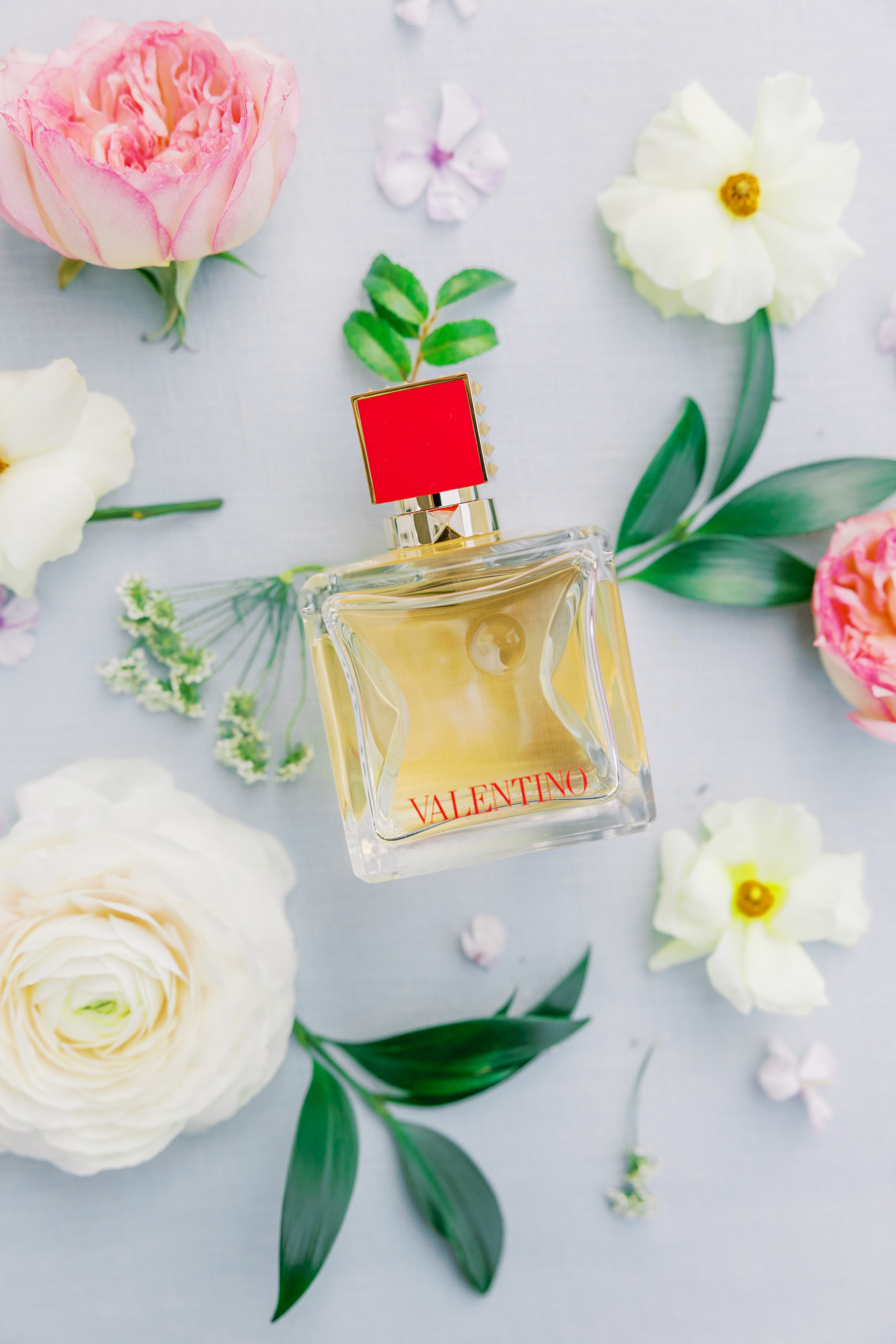 Valentino perfume with red cap and pink and cream flowers and leaves for New Hampshire Wedding Photography