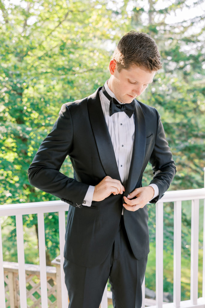 Groom buttons up black tuxedo jacket 