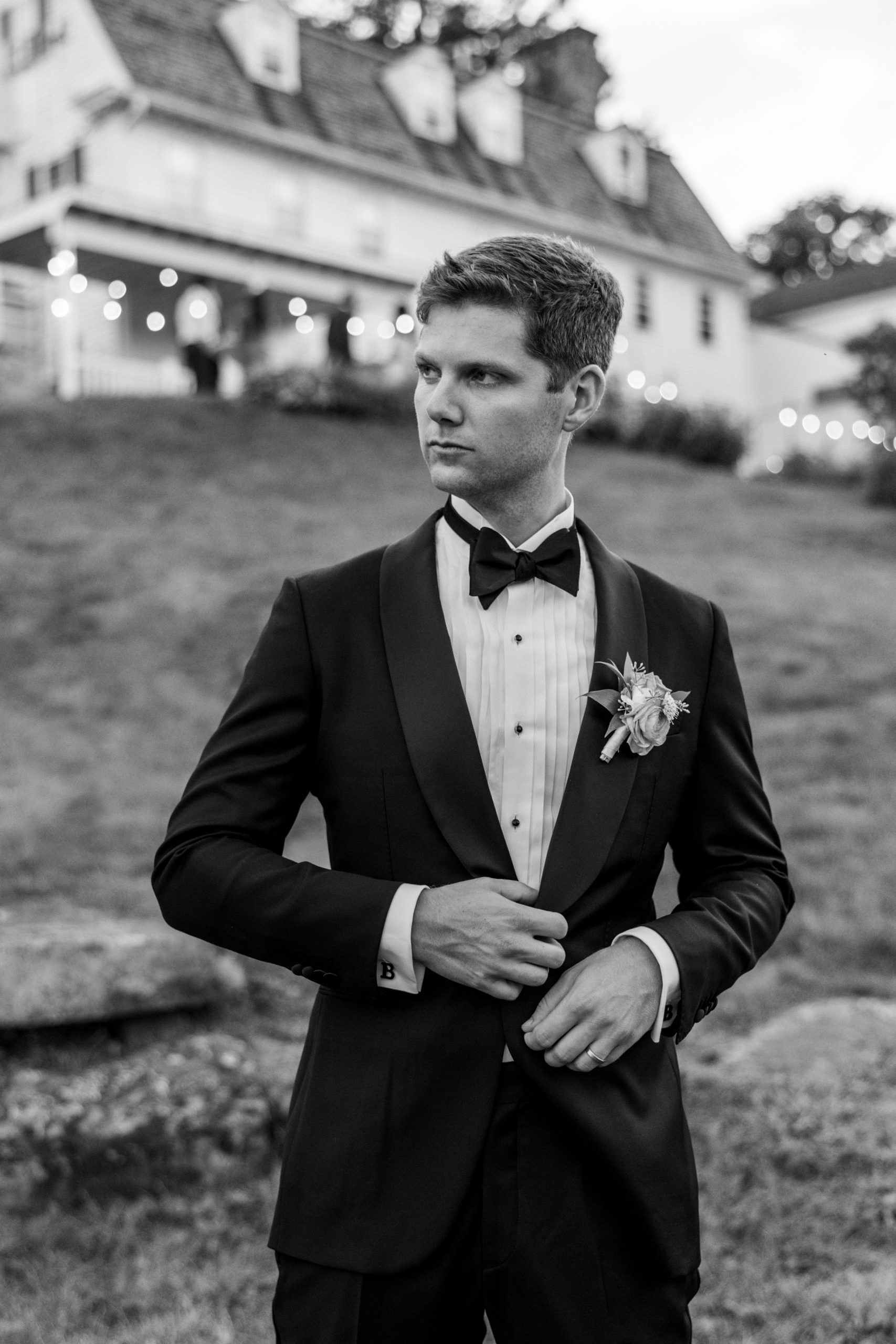 Groom poses looking to the side and adjusts jacket 