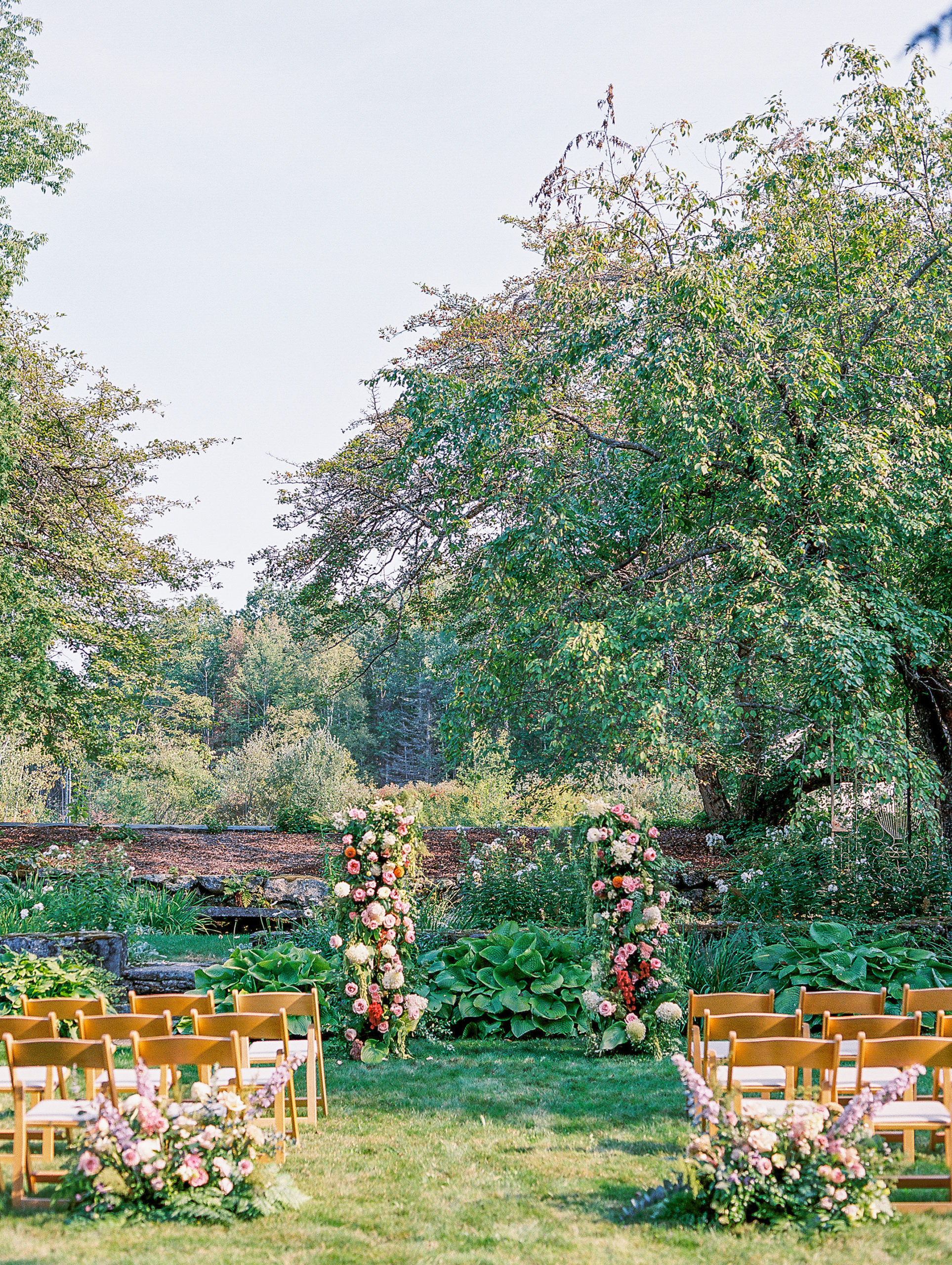 Wedding ceremony aisle with trees and pink and cream flowers for New Hampshire Wedding Photography