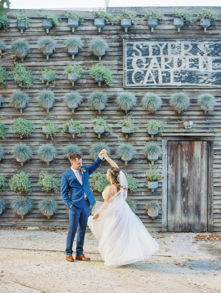 Groom spins bride in from of rustic garden cafe at terrrain for Terrain Glen Mills Wedding