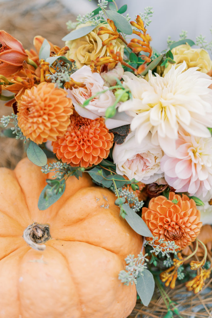 Up close view of wedding bouquet with orange and cream flowers with pumpkin for Terrain Glen Mills Wedding