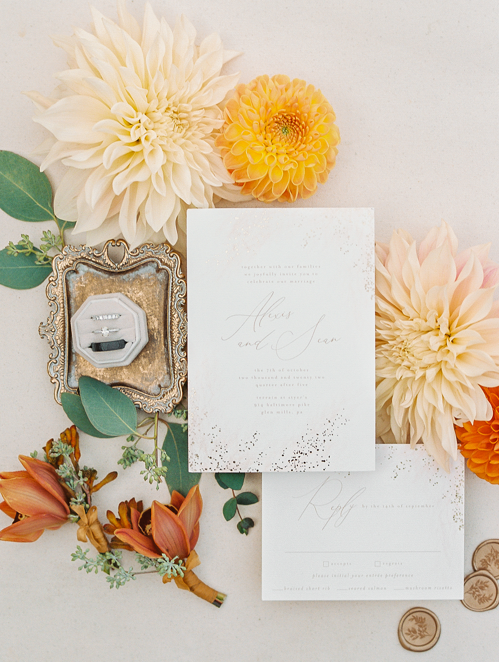Cream and sparkled invitations with ring box atop gold tray, and yellow, orange, and cream flowers for Terrain at Styer's Wedding