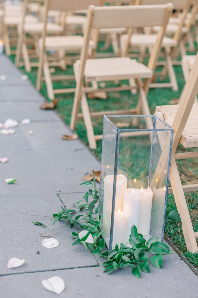 Candles in glass rectangular boxes line the stone aisle for Terrain at Styer's Wedding