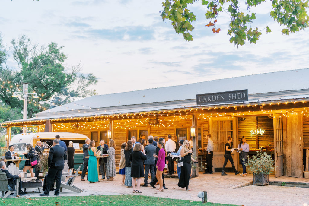 Guests mingle at outdoor social area along garden shed for Terrain Glen Mills Wedding