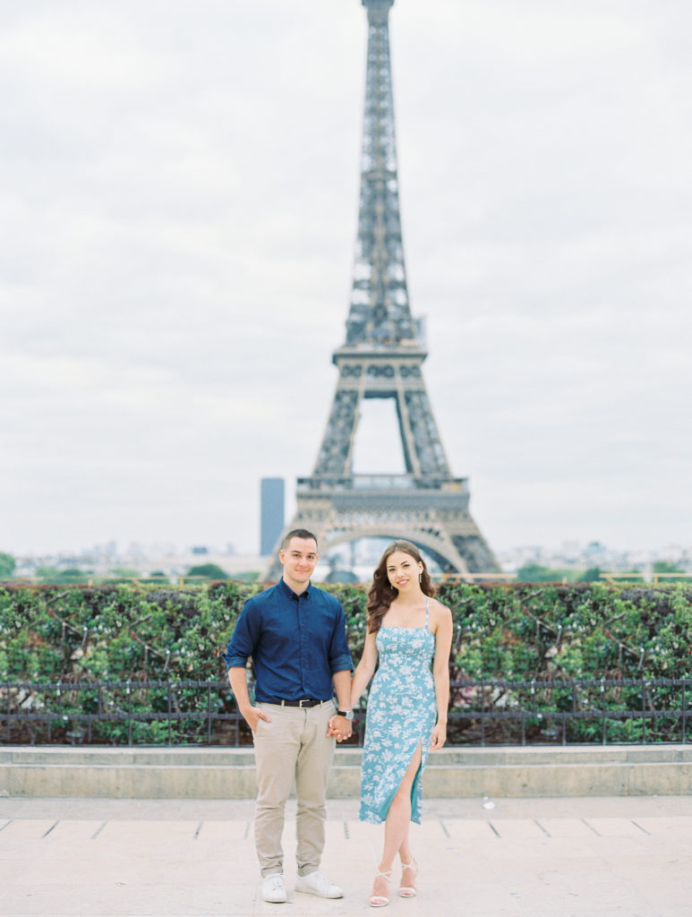 Couple holds hands and poses in front of Eiffel Tower for Paris Film Photographer