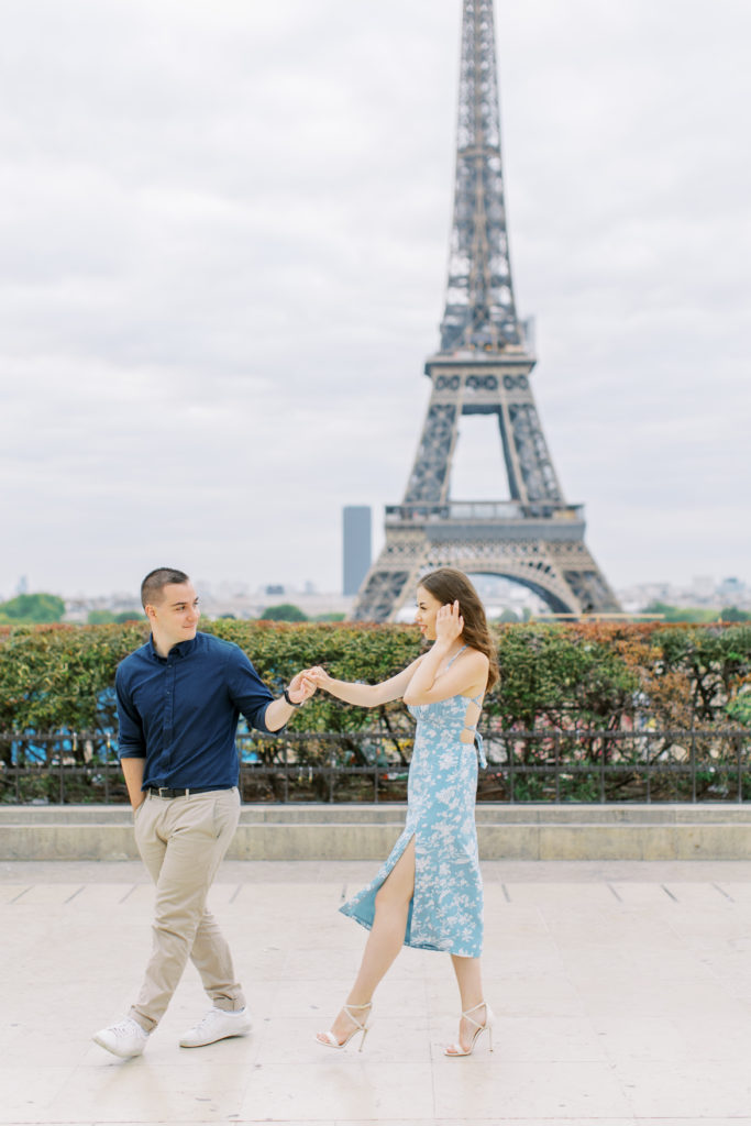 Couple walks on stone pathway with Eiffel Tower in background 