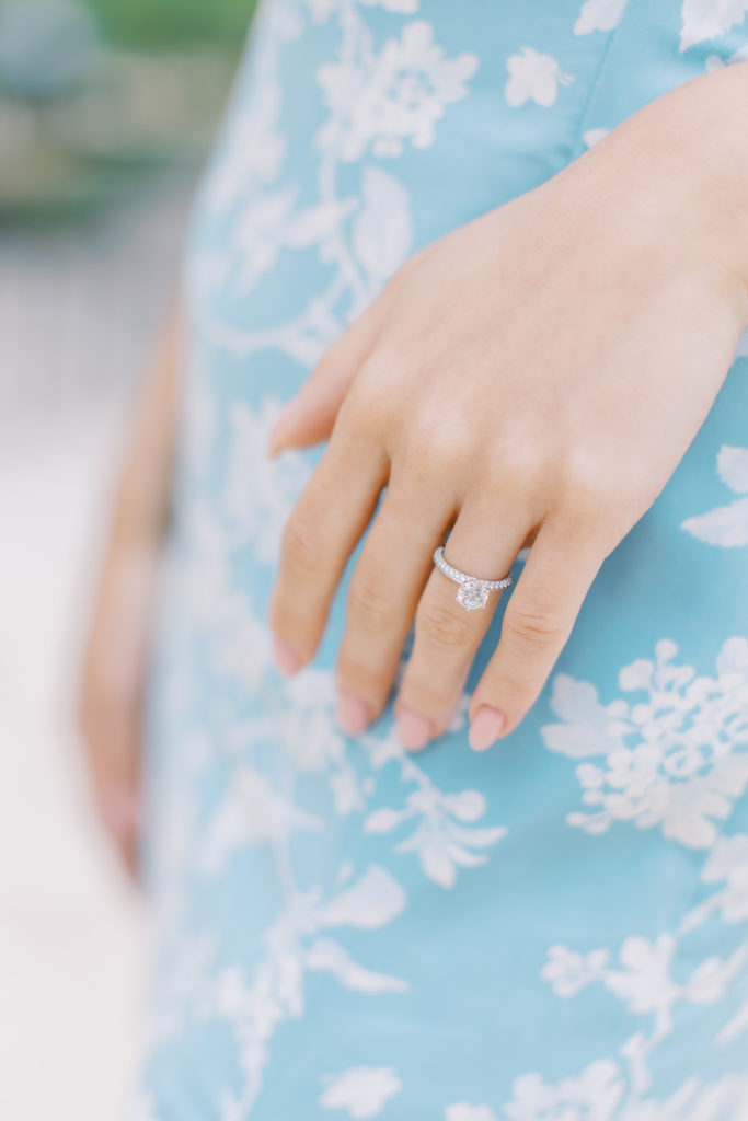 Up close of view of engagement ring on hand with blue and white floral dress for Paris Engagement Session