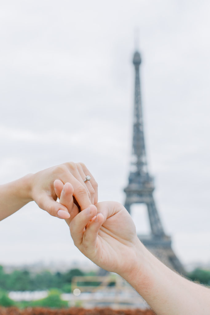 Up close view of couple's hands and engagement ring with Eiffel Tower in background for Paris Engagement Session