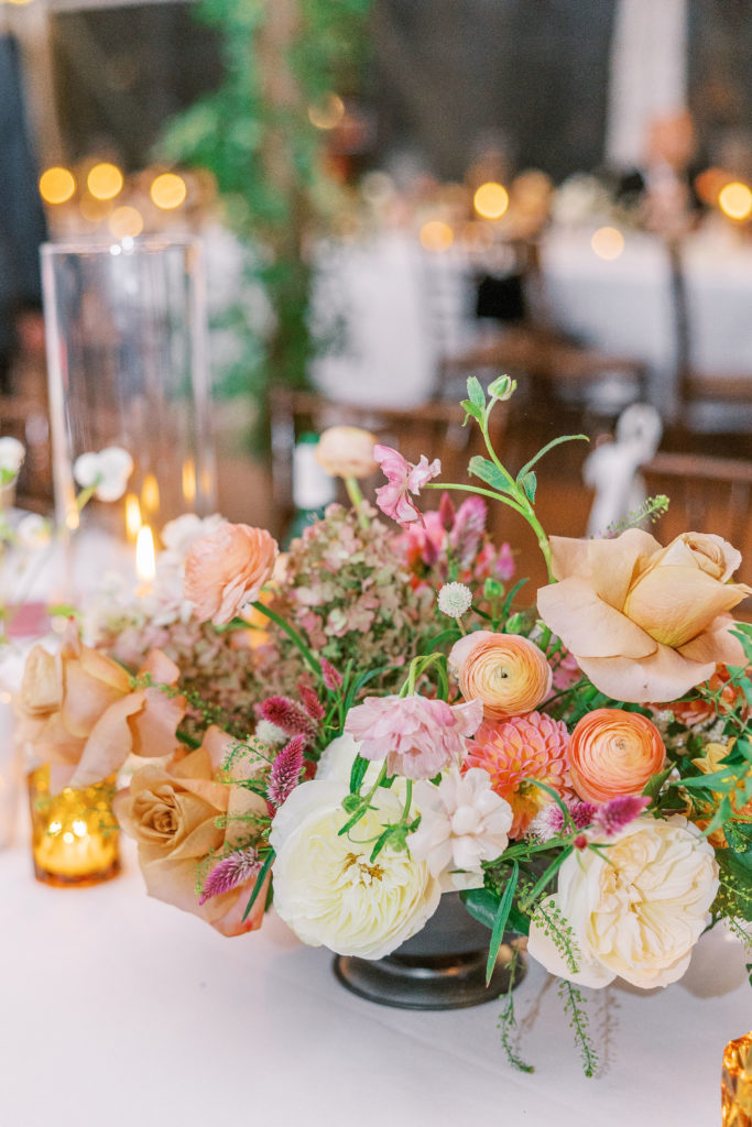 View of flower arrangement as centerpiece with ivory, peach, and pink flowers 
