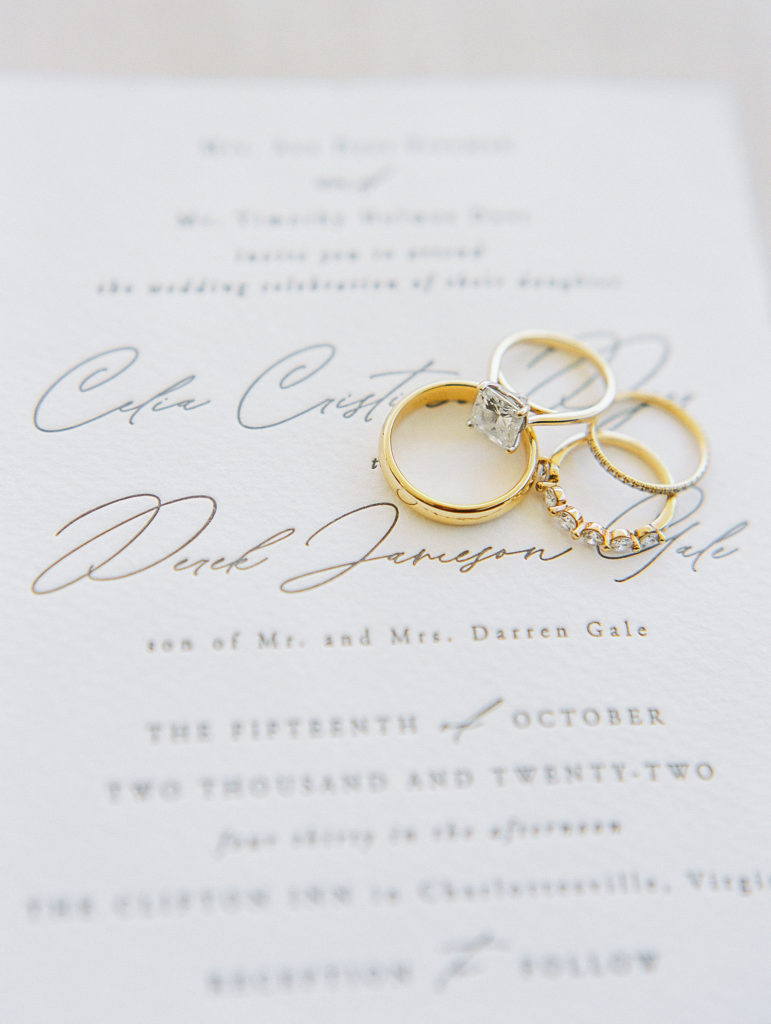 Wedding rings on top of cream colored invitations with delicate calligraphy 