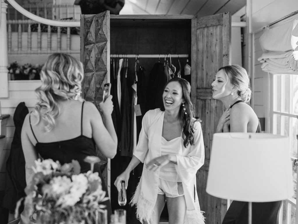Bride laughs as she starts to get ready with bridesmaids and they snap a photo of her on iPhone for Clifton wedding photography