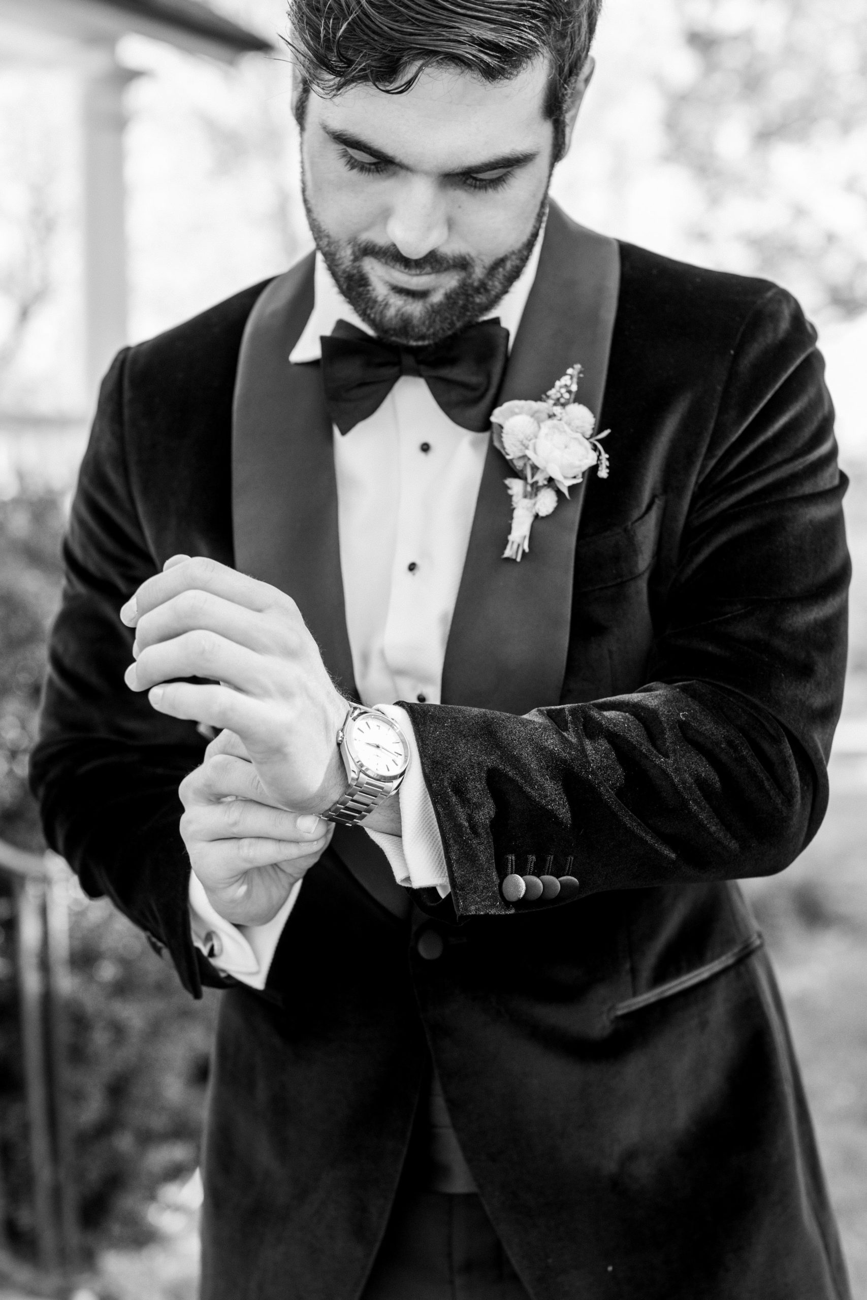 Groom fixes watch wearing black suit and bowtie for Clifton wedding photography