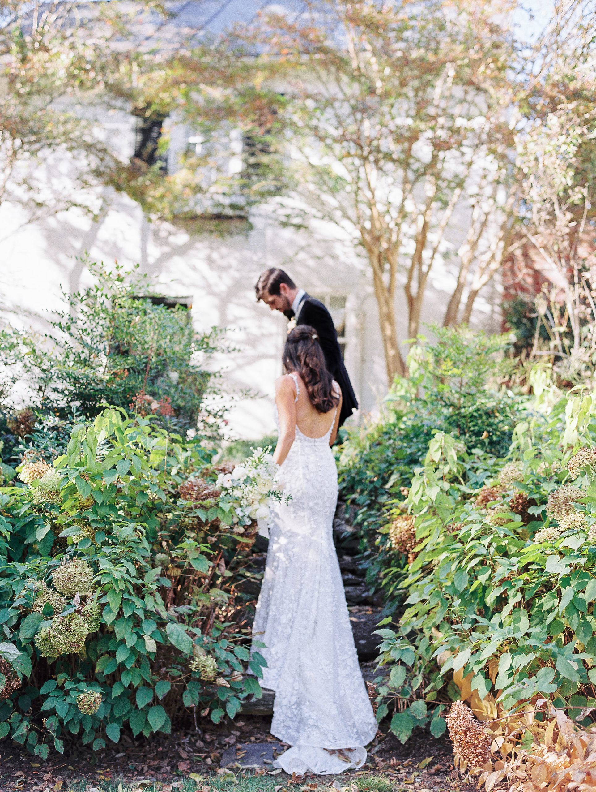 Groom leads bride up stone stairs in garden for Clifton wedding photography