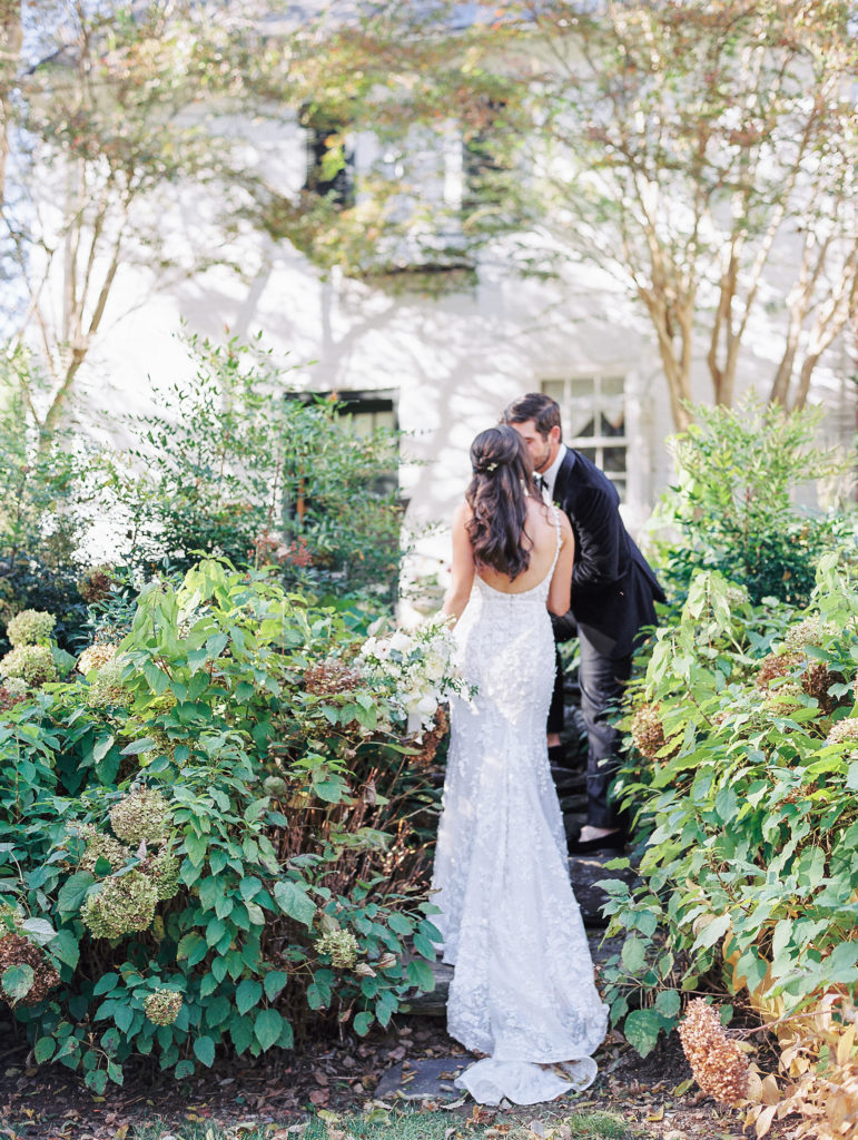 Groom leads bride up stone stairs in garden and gives her a kiss for Clifton wedding photography