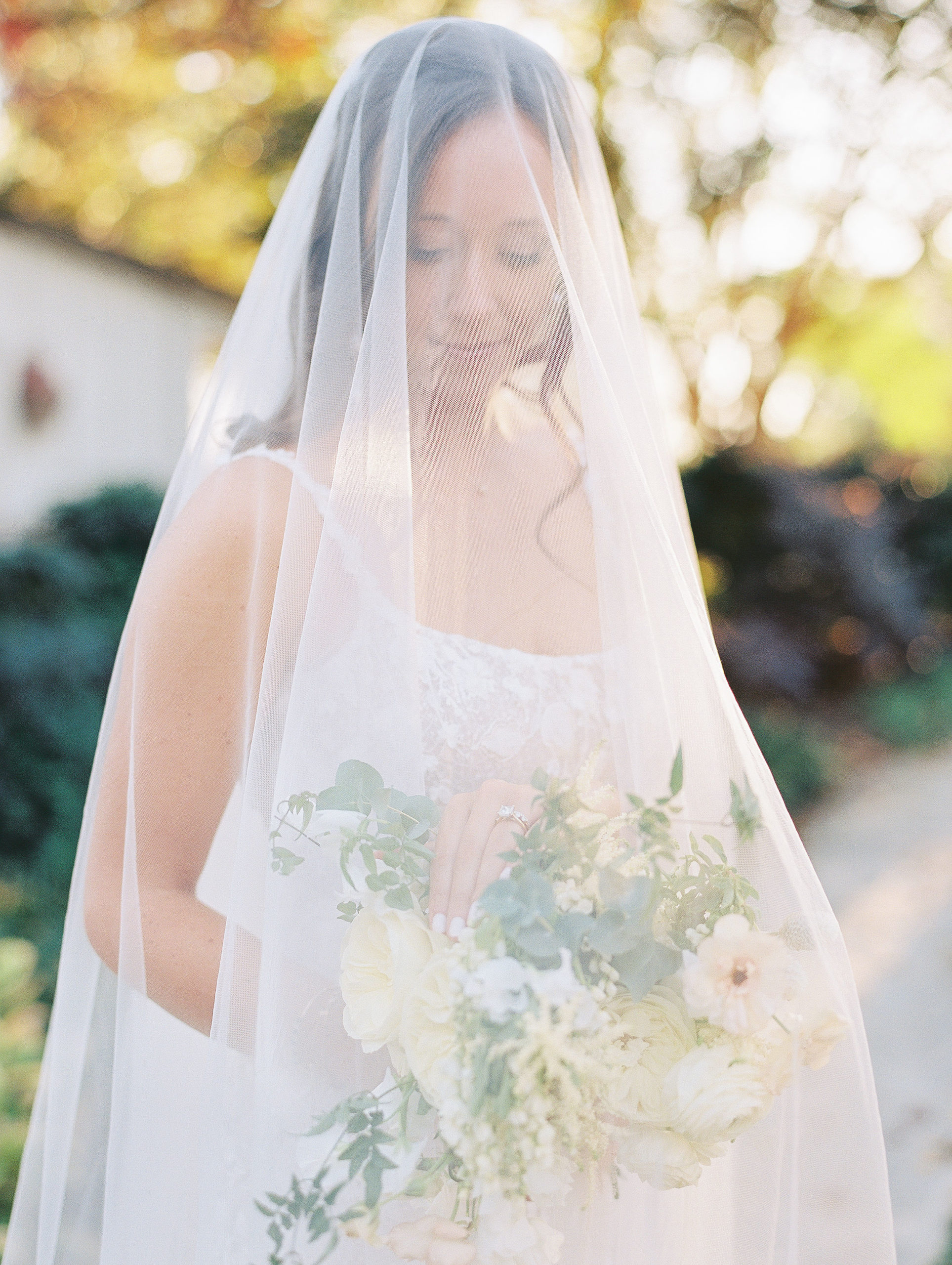 Bride holds bouquet and looks down with veil over head for Clifton wedding photography