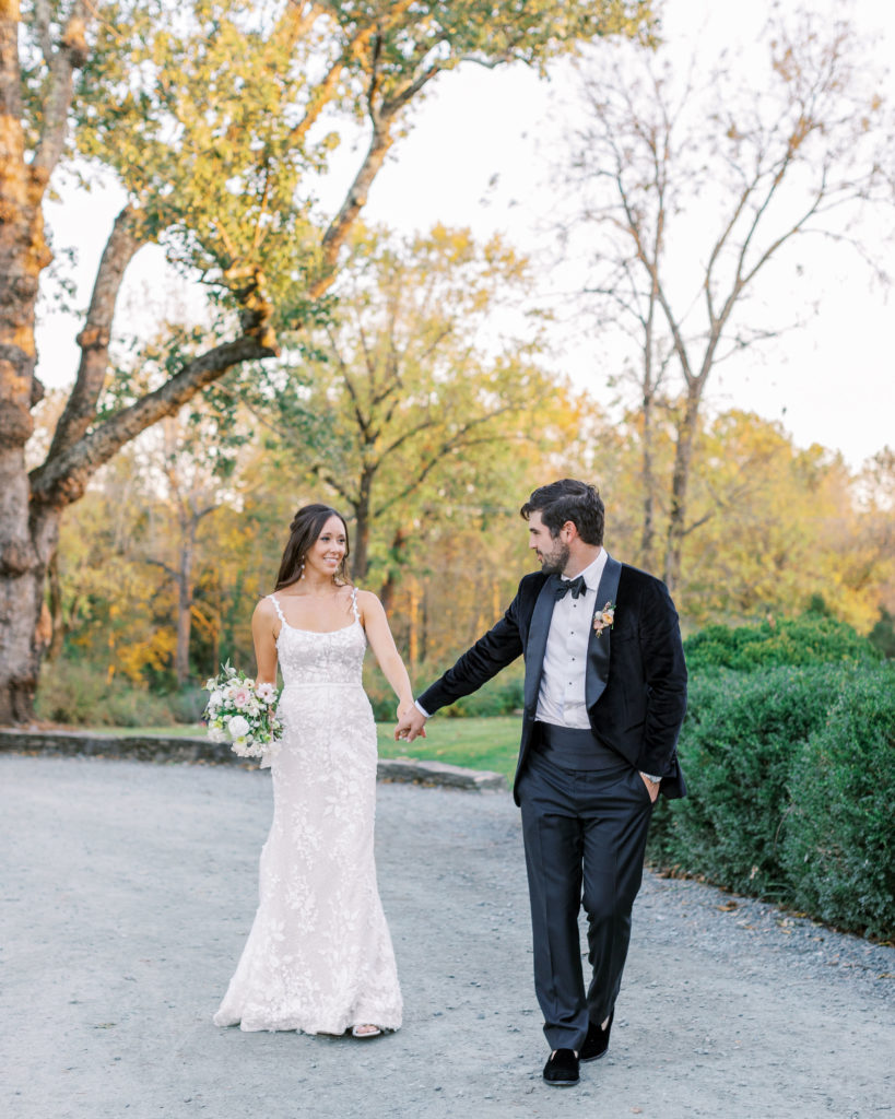 Bride walks on gravel pathway outside holding hands for Clifton wedding photography