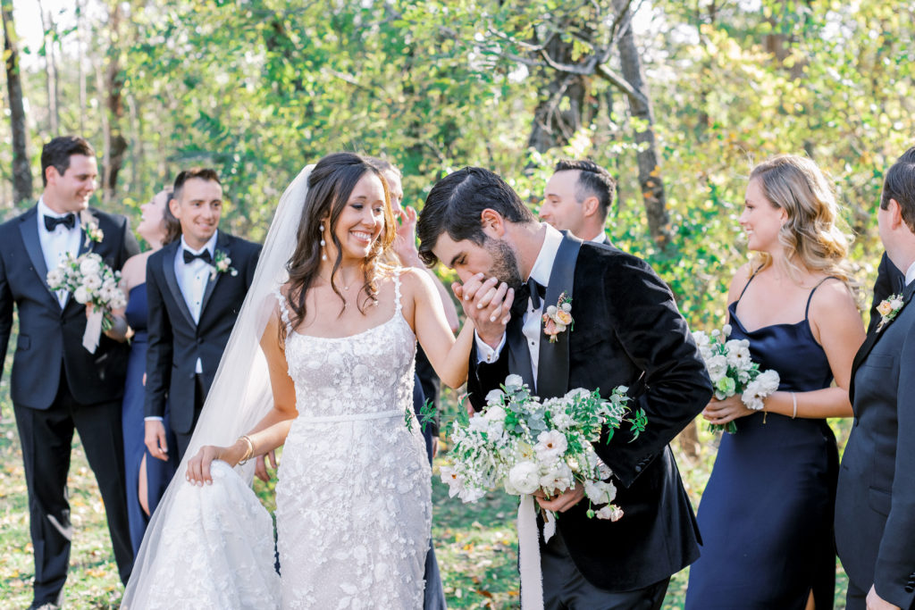 Groom kisses bride's hand and holds bouquet for Clifton wedding photography