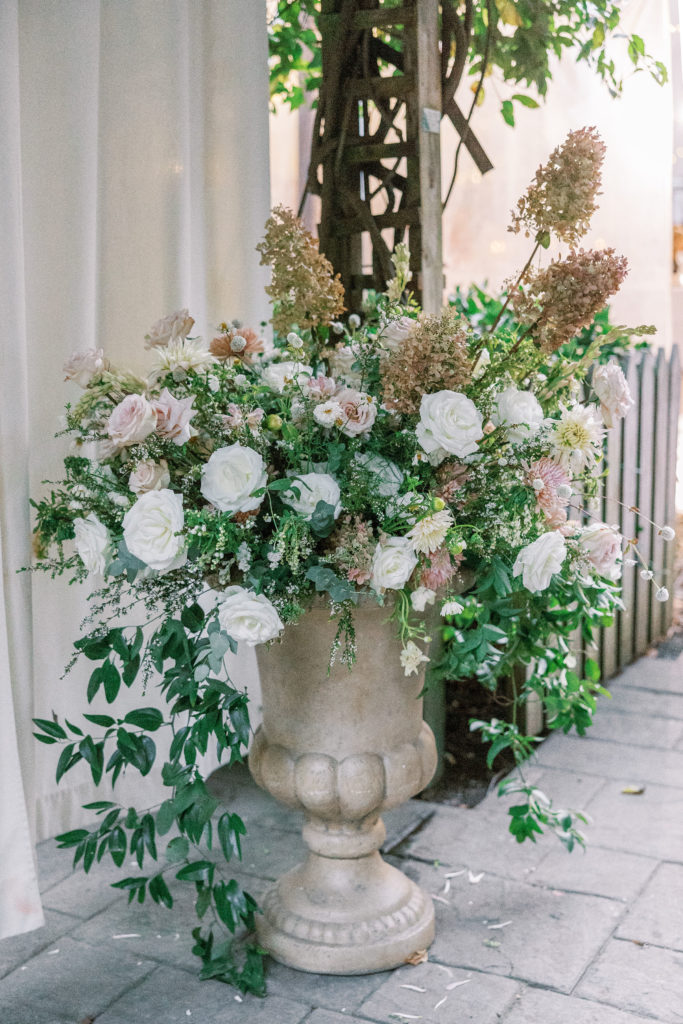 White roses and pink flower arrangement in large stone pot 