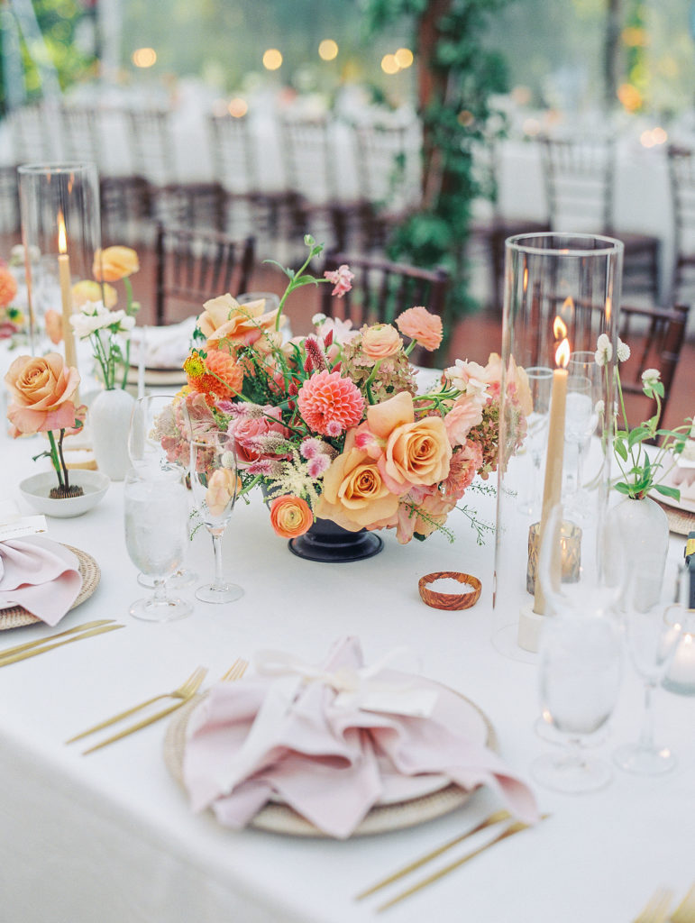 View of peach and pink flower arrangement and tall candles in vases for reception tables for Clifton wedding photography