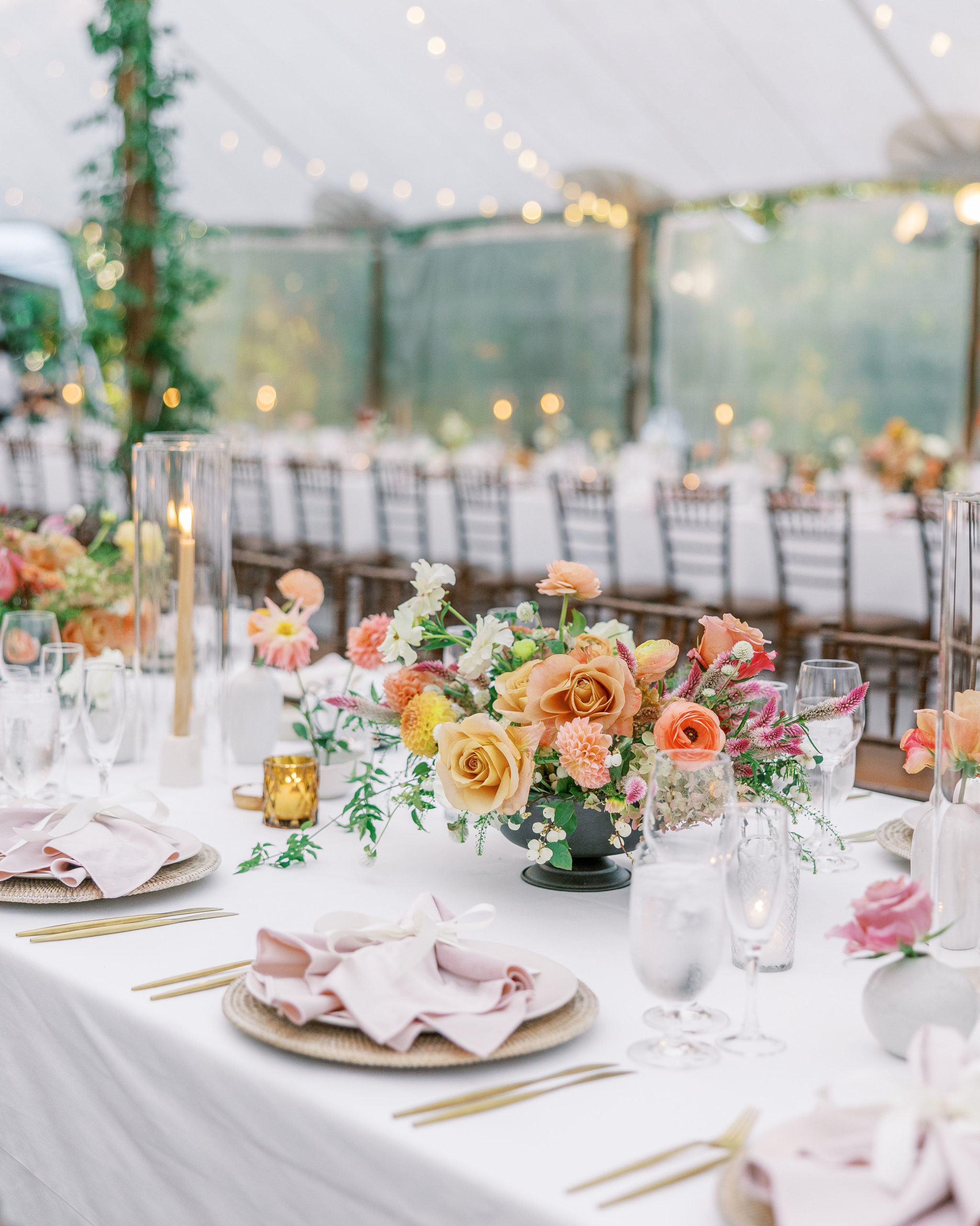 Wedding reception tables with peach and pink flower arrangements, tall candles, and pink napkins for Clifton wedding photography