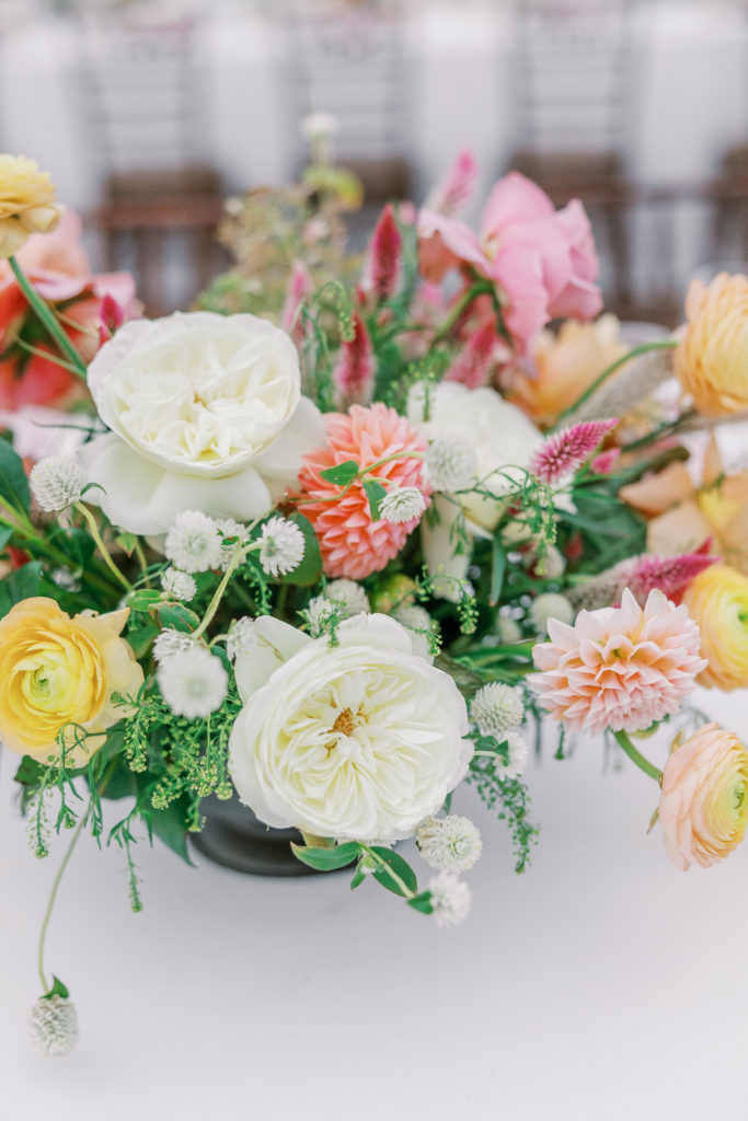 White, pink, and yellow flower centerpiece in black low vase 