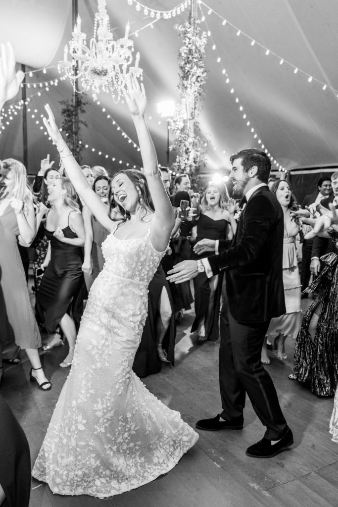 Bride puts her arms up singing on the dance floor with guests dancing for Clifton wedding photography
