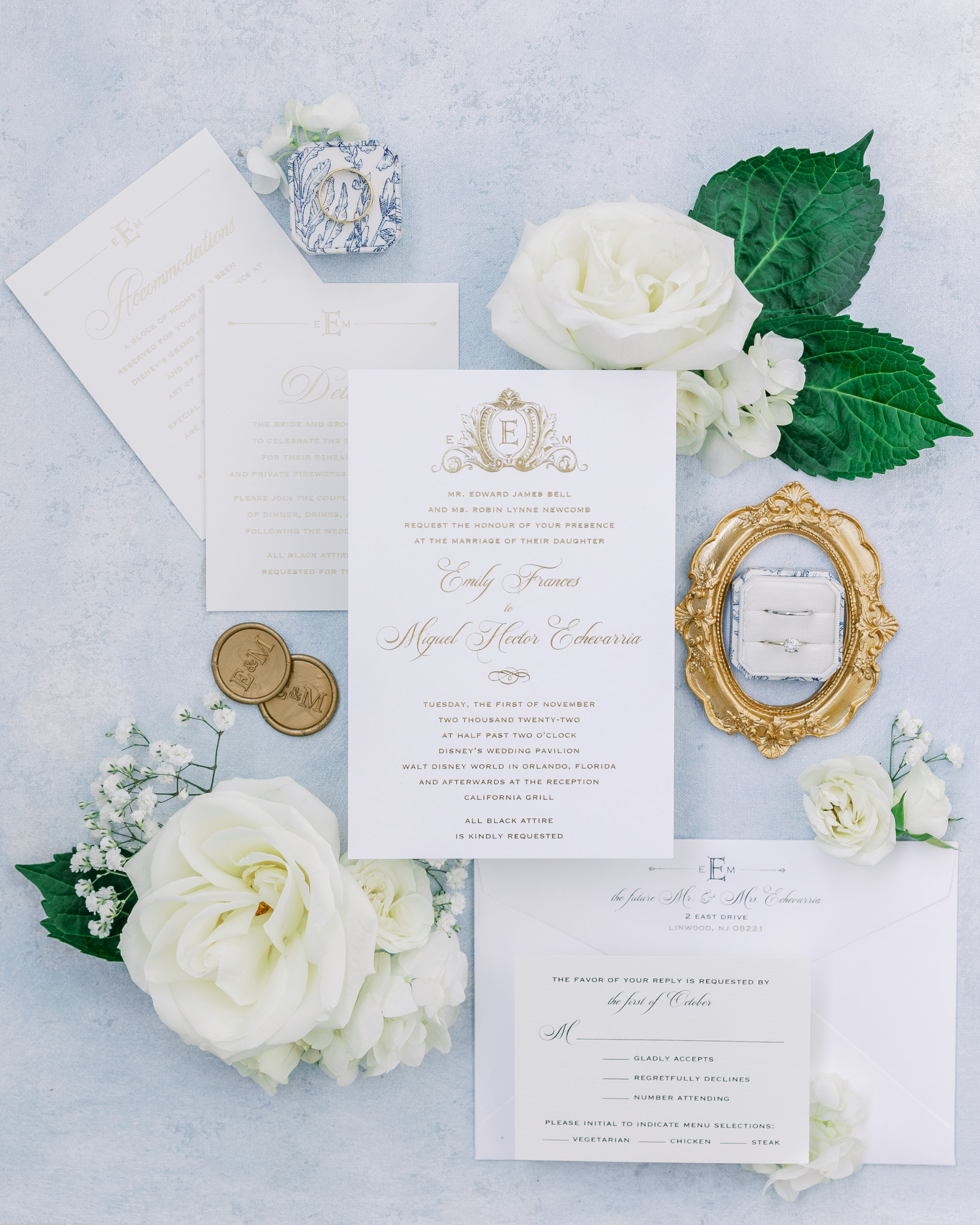  Ivory and cream wedding invitations with gold caligraphy, ring box laying on gold frame, and white roses for California Grill Wedding