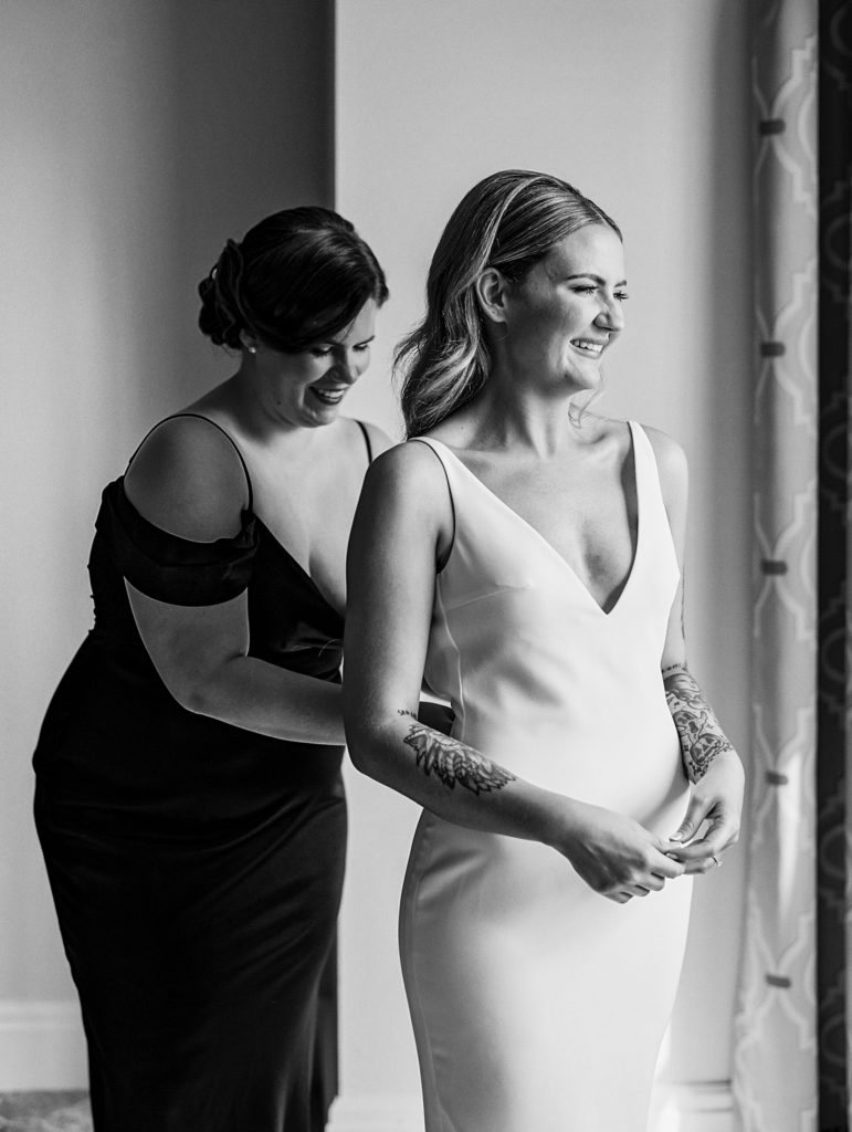 Bride gets help with dress as they laugh for California Grill Wedding